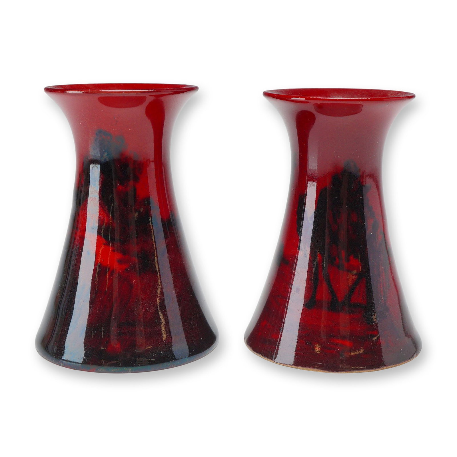 Pair of Royal Doulton Flambe Landscape Motif Miniature Vases: Pair of flambe mini glazed ceramic vases with a waisted, flared-rim silhouette. One vase is decorated with a black underglaze silhouette design depicting a desert scene with camels and palm trees. The