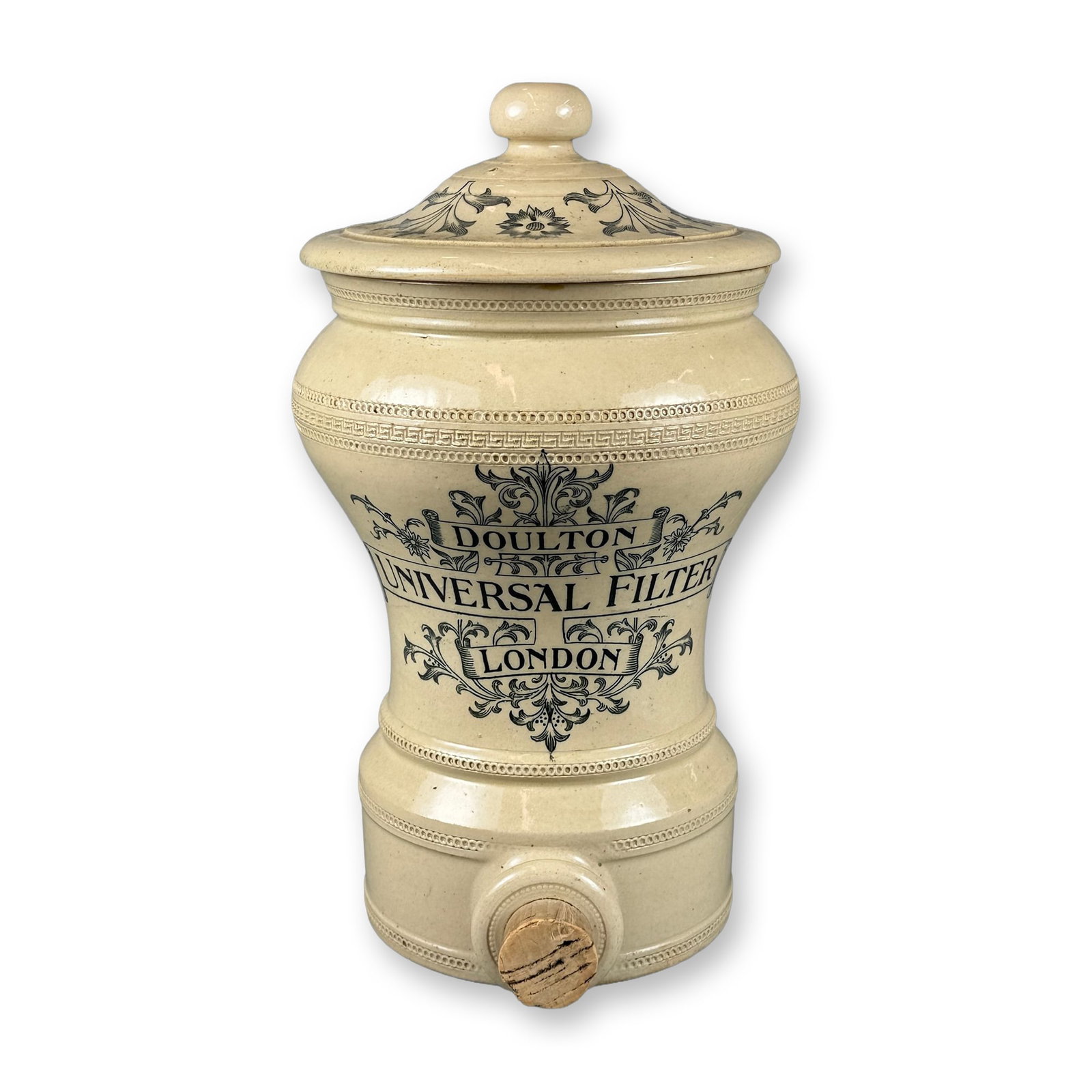 Doulton Lambeth Stoneware Salt-Glazed Universal Filter with Lid: Decorated with coat of arms and foliate motif. Lid with floral designs. Inscribed "DOULTON UNIVERSAL FILTER LONDON". Includes a period carbon filter and decorative lid. Dimensions: 10"L x 9"W x 15"H M