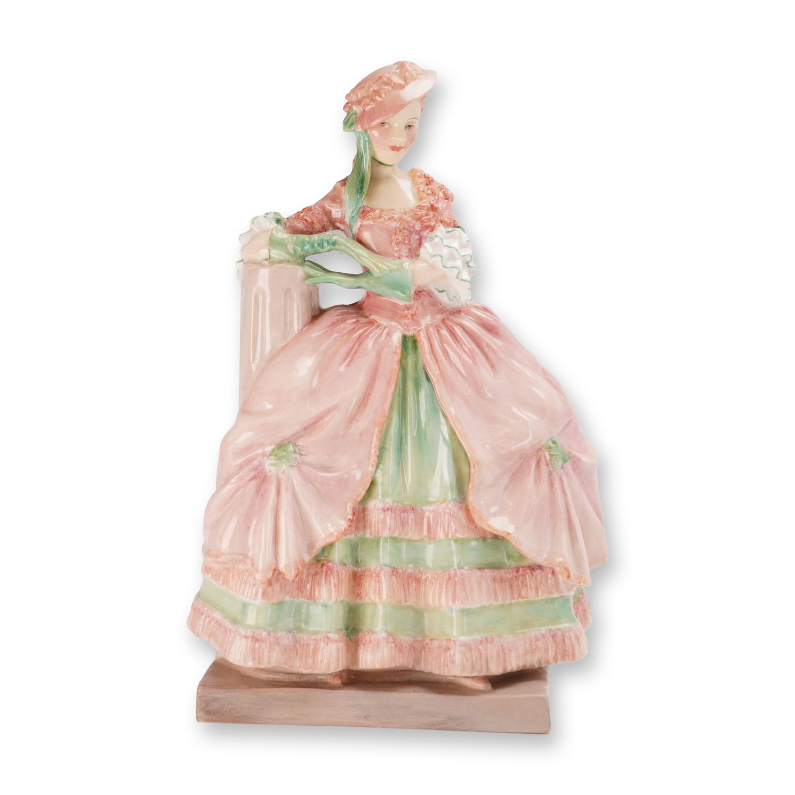 Royal Doulton Porcelain Figurine, Kate Hardcastle HN1718: Designed by Leslie Harradine. The figure wears a voluminous pink gown with pale green accents and tiered ruffles, complemented by a pink hat with green ribbons, and is shown leaning against a classica
