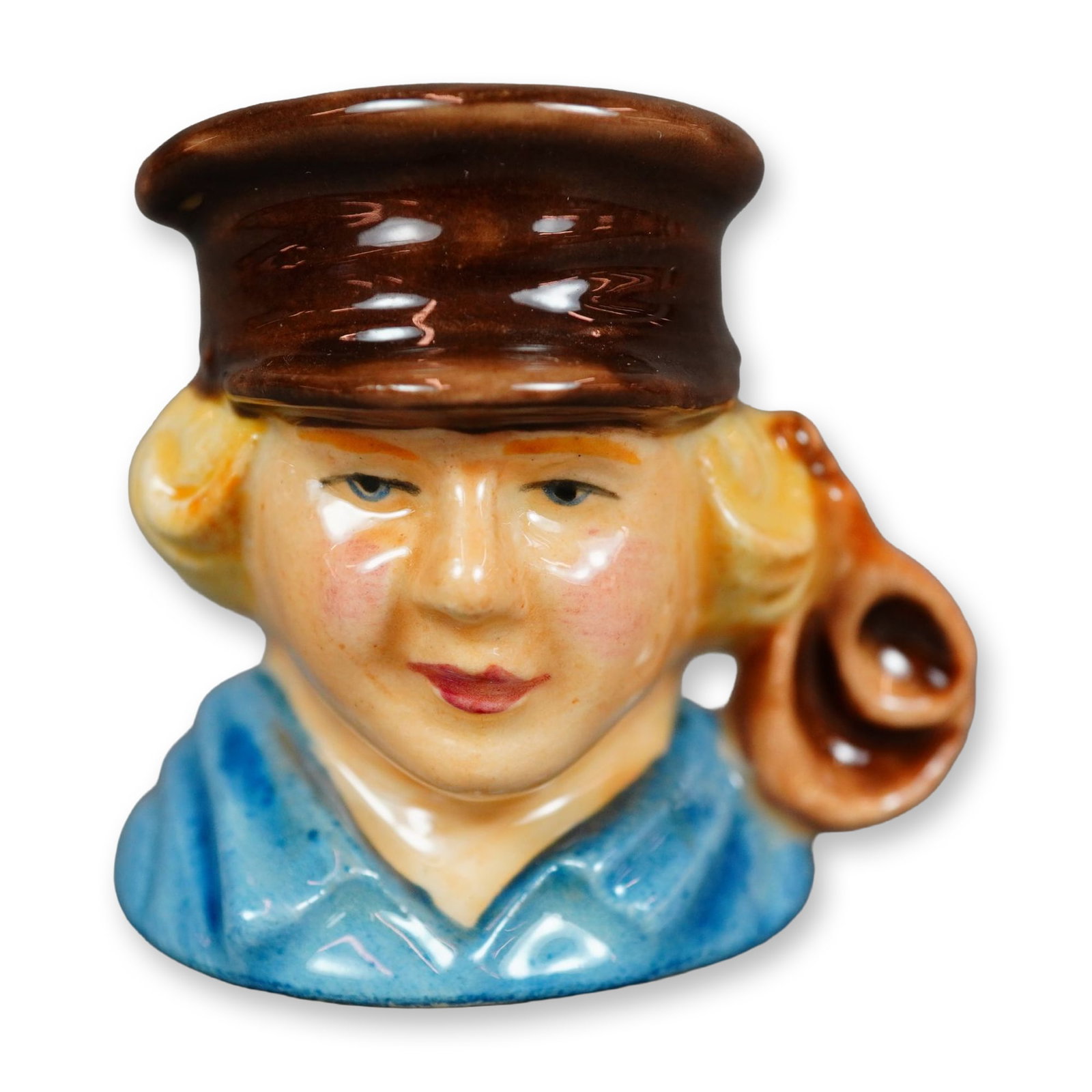 Royal Doulton Prototype Tiny Character Jug, Oliver Twist: A figural jug depicting Oliver Twist, the titular protagonist of the 1838 novel by Charles Dickens and the first child protagonist in a British novel. The character is shown wearing a blue shirt and b