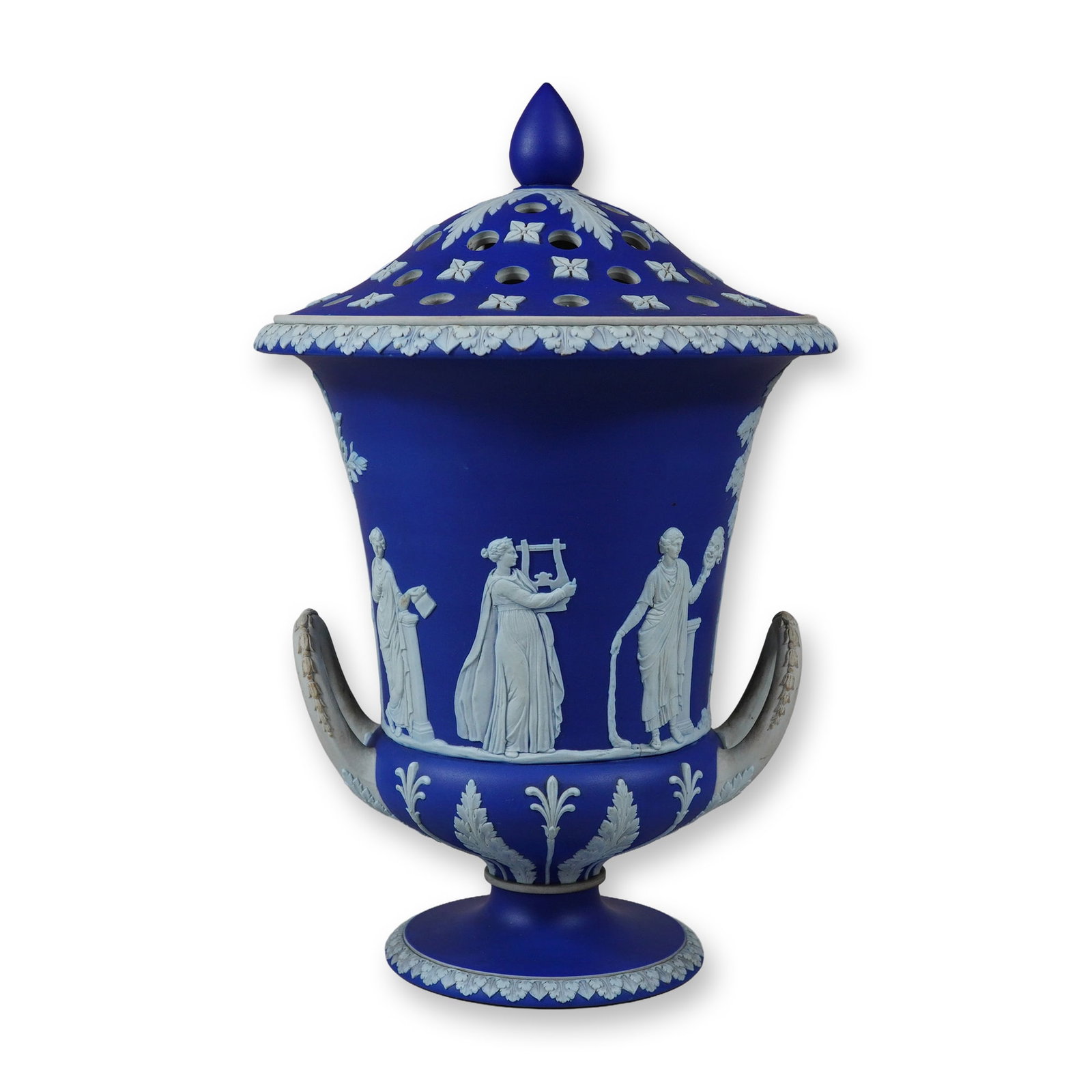 Wedgwood Dark Blue Jasperware Campana Covered Potpourri Vase: A Wedgwood cobalt blue jasperware potpourri vase of campana form featuring a matching perforated cover. The matte-finish dark blue stoneware body is decorated with applied white relief ornamentation. 
