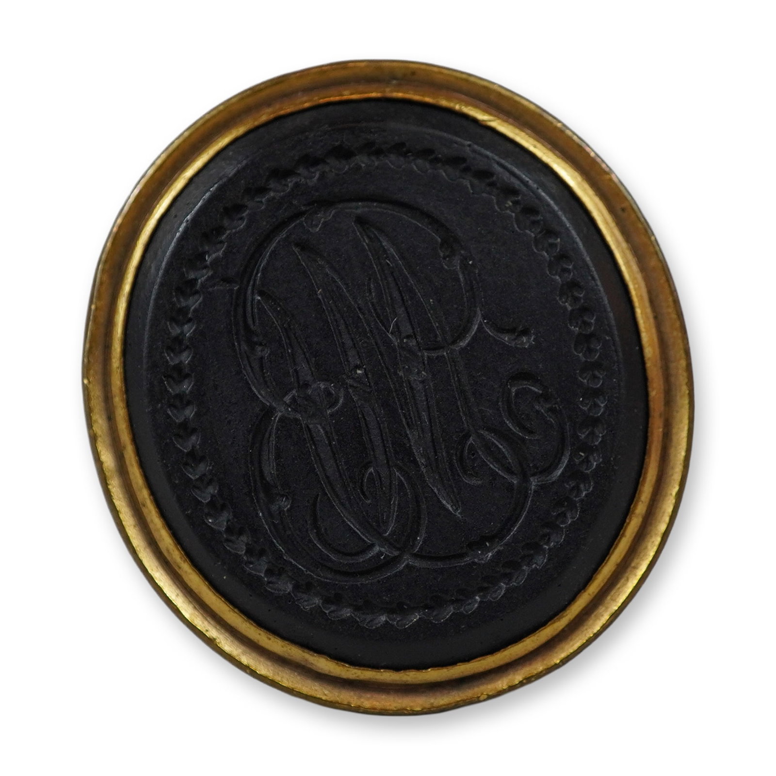 Wedgwood and Bentley Black Basalt Monogrammed Fob Seal: An antique fob seal featuring a black basalt intaglio bezel-set into a gold-toned metal mount. The oval stoneware intaglio is engraved with a decorative script monogram, surrounded by a beaded border.