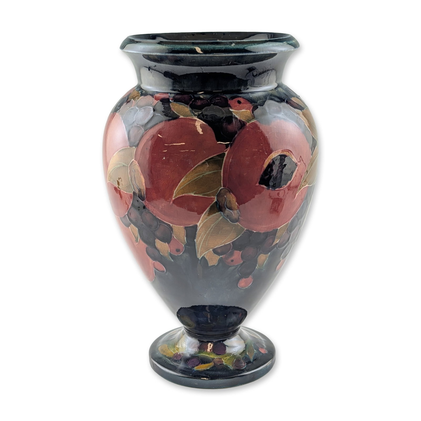 Moorcroft Pottery Urn Shape Vase, Pomegranate: The footed baluster form features a flared rim and is decorated with tube-lined and hand-painted fruit and foliage in tones of deep red, ochre, and purple against a dark cobalt blue ground. The unders
