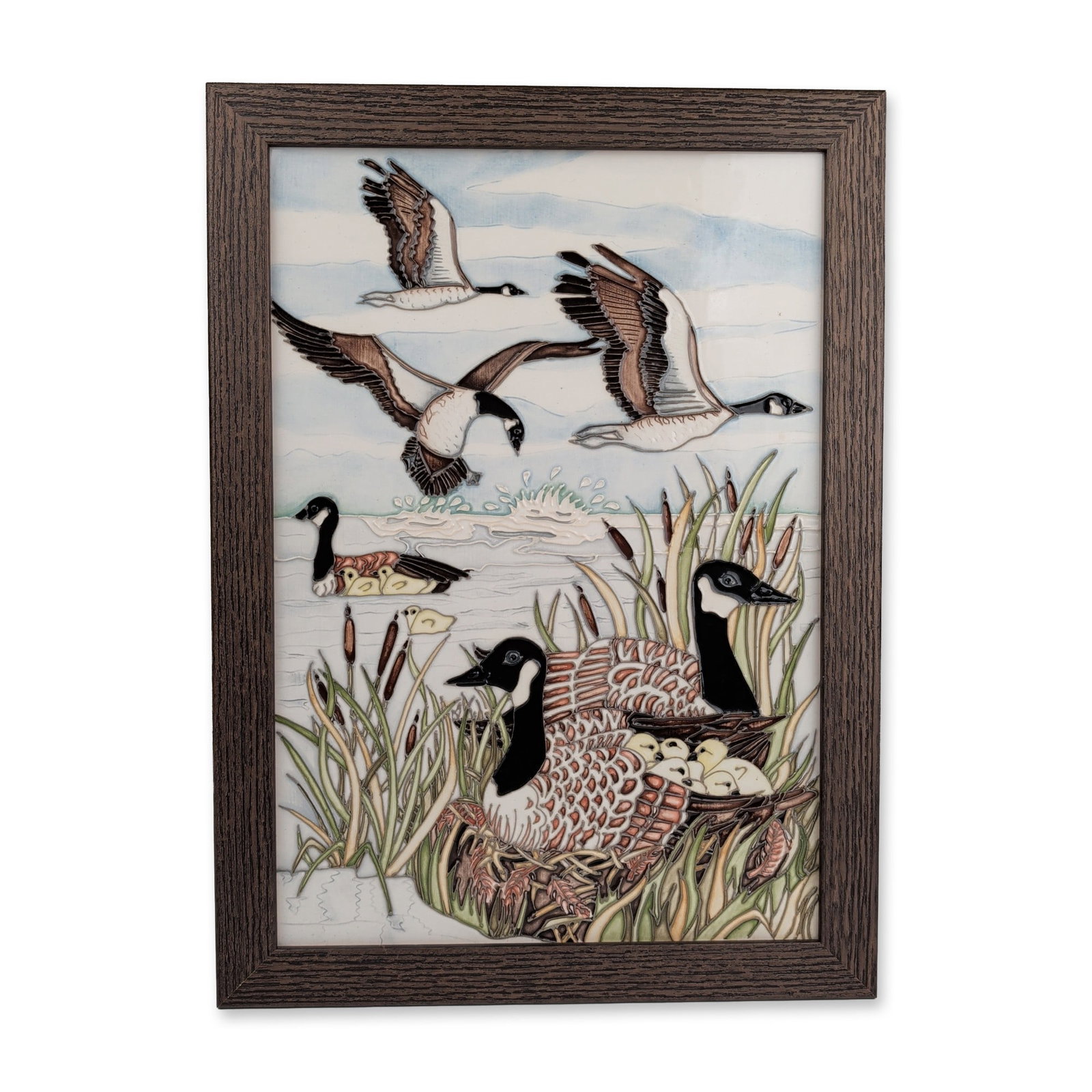 Moorcroft Pottery by Helen Dale and Anji Davenport Framed Tile, The Gathering: The piece depicts Canada geese in flight and nesting within a landscape of reeds and bullrushes, executed in multicolored glazes. The tile is housed in a dark brown wood grain frame and is accompanied