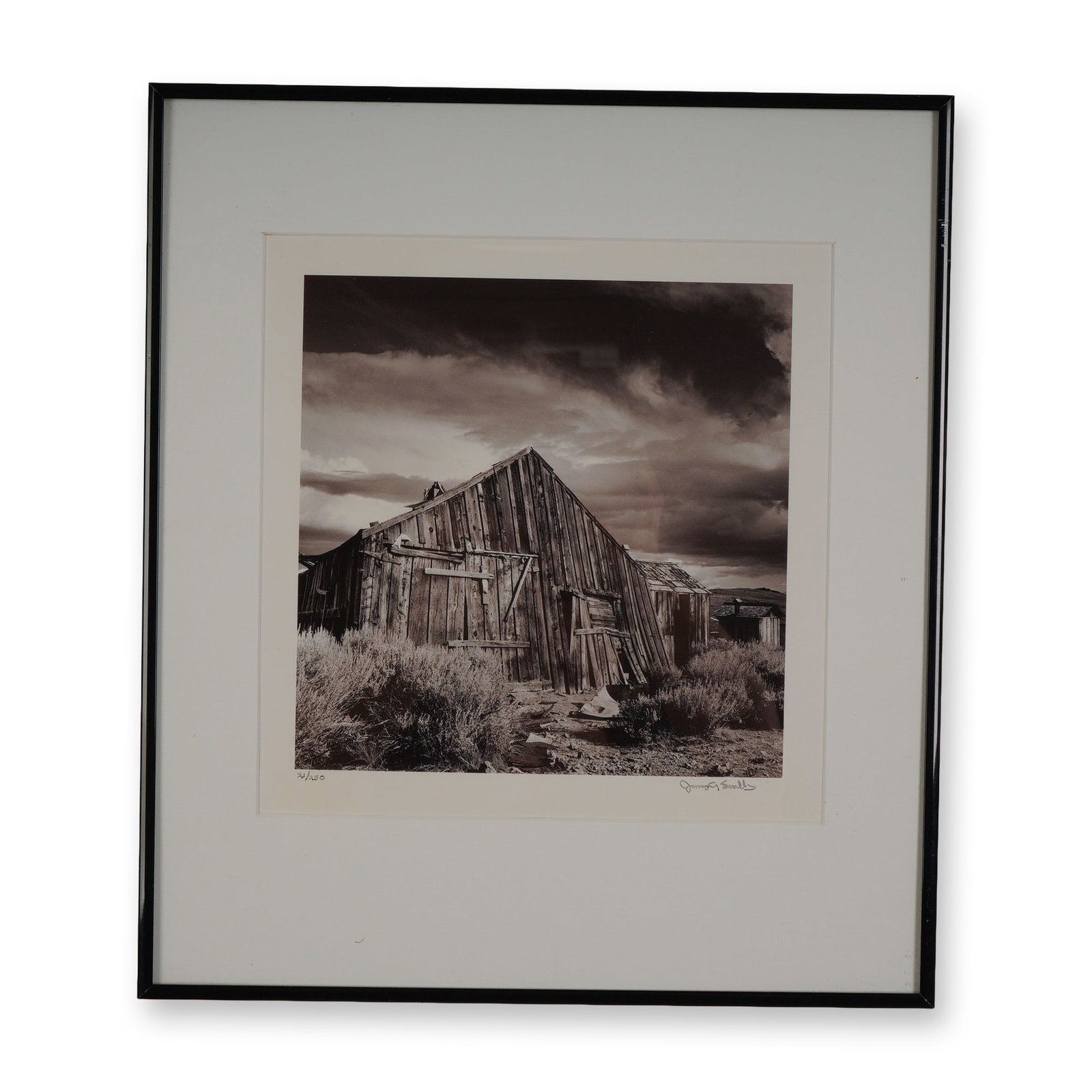 James A Swallow, B&W Photograph, Waiting till the Next, Signed: A striking limited edition black and white photograph by James A. Swallow, titled Waiting Till the Next. This atmospheric image captures a weathered wooden structure beneath dramatic skies in a desola