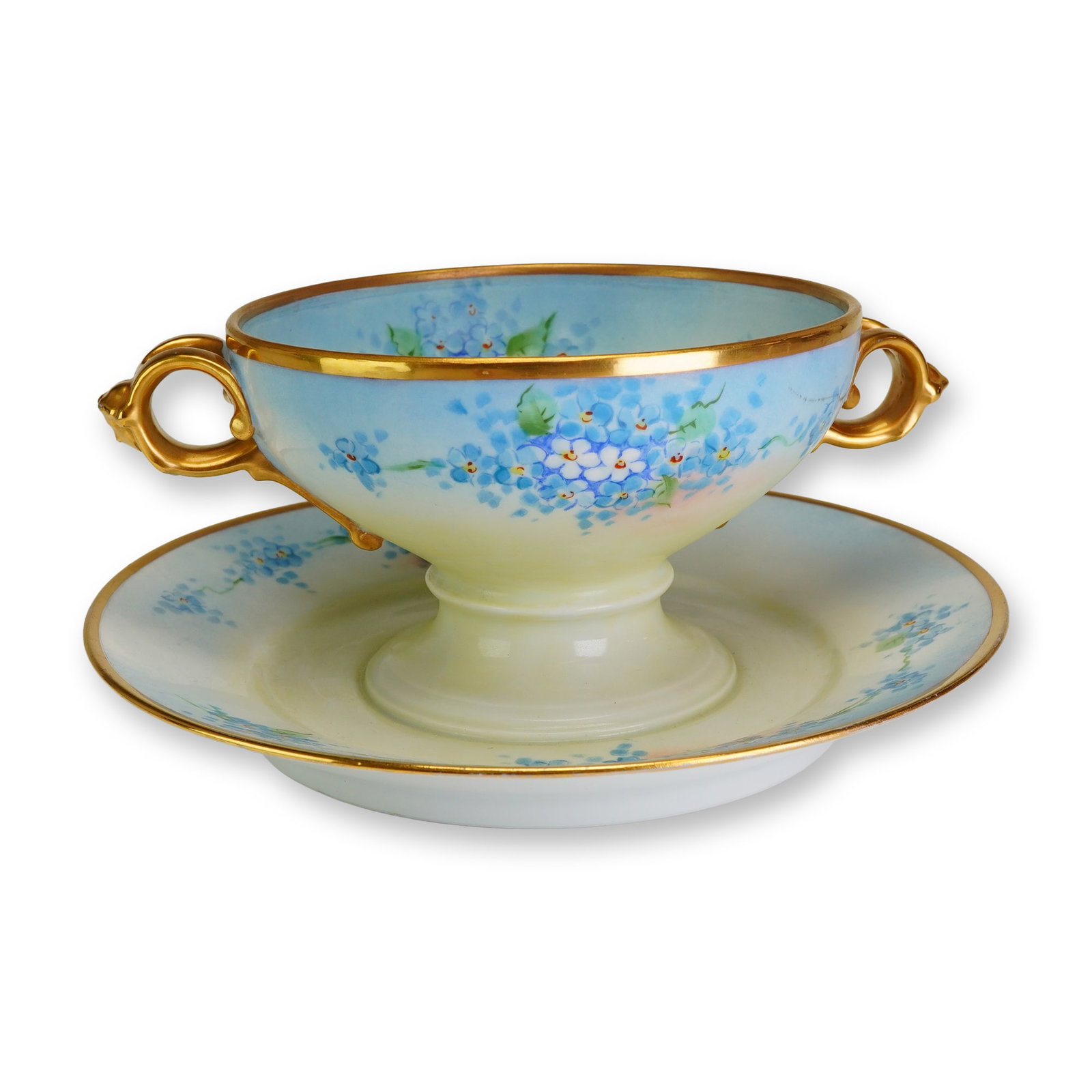 Rosenthal Porcelain Bullion Cup on Integral Undertray, Forget-Me-Not: A small footed bowl with two handles, fixed to an undertray. Decorated with a floral motif of forget-me-nots on a shaded ground transitioning from light blue to cream, with blue blossoms, green foliag