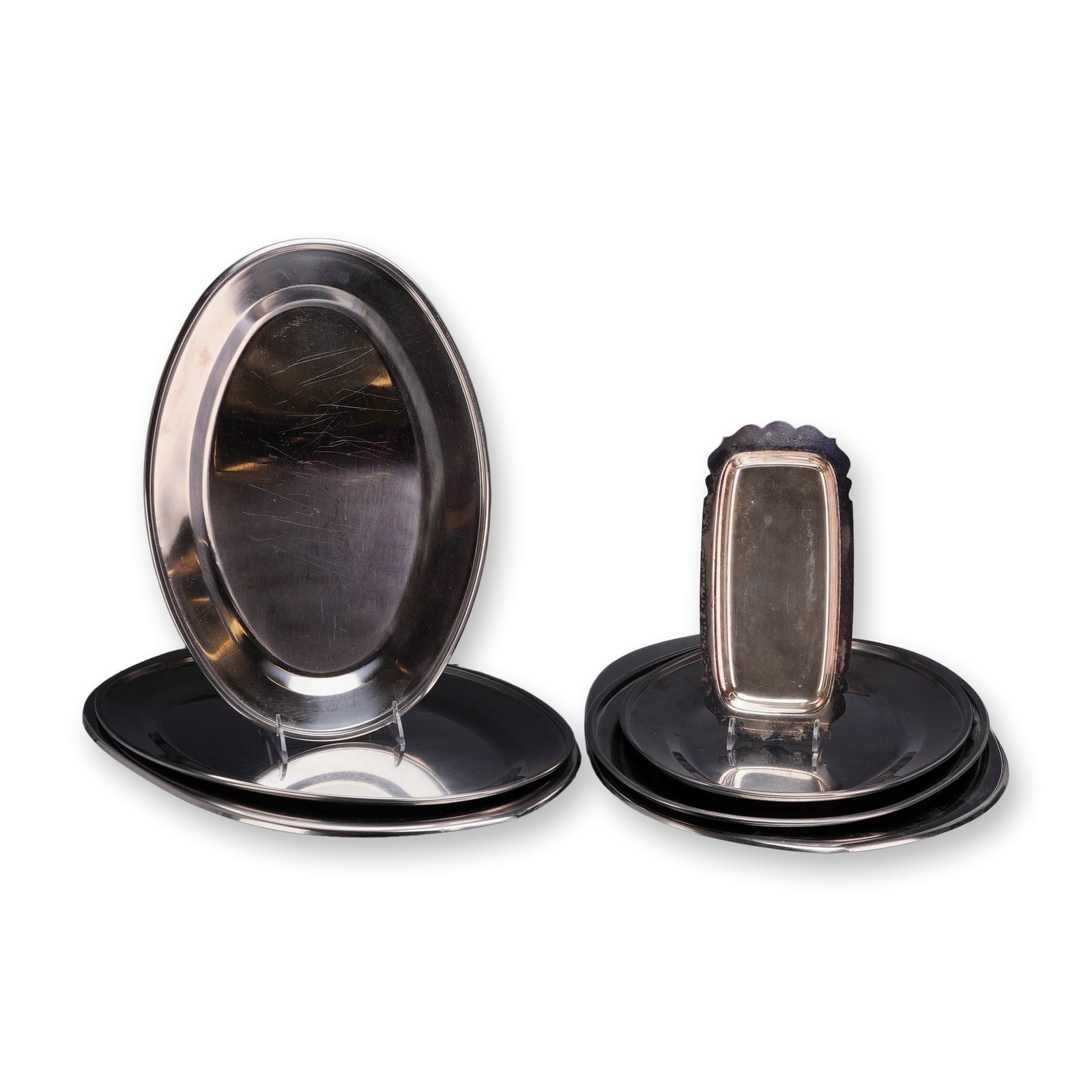 Set of 7 Stainless Steel Platters and a Scalloped Serving Dish: The group includes 7 platters of graduated sizes in both oval and round shapes, along with a small rectangular serving dish. Each item is constructed from polished stainless steel and features a