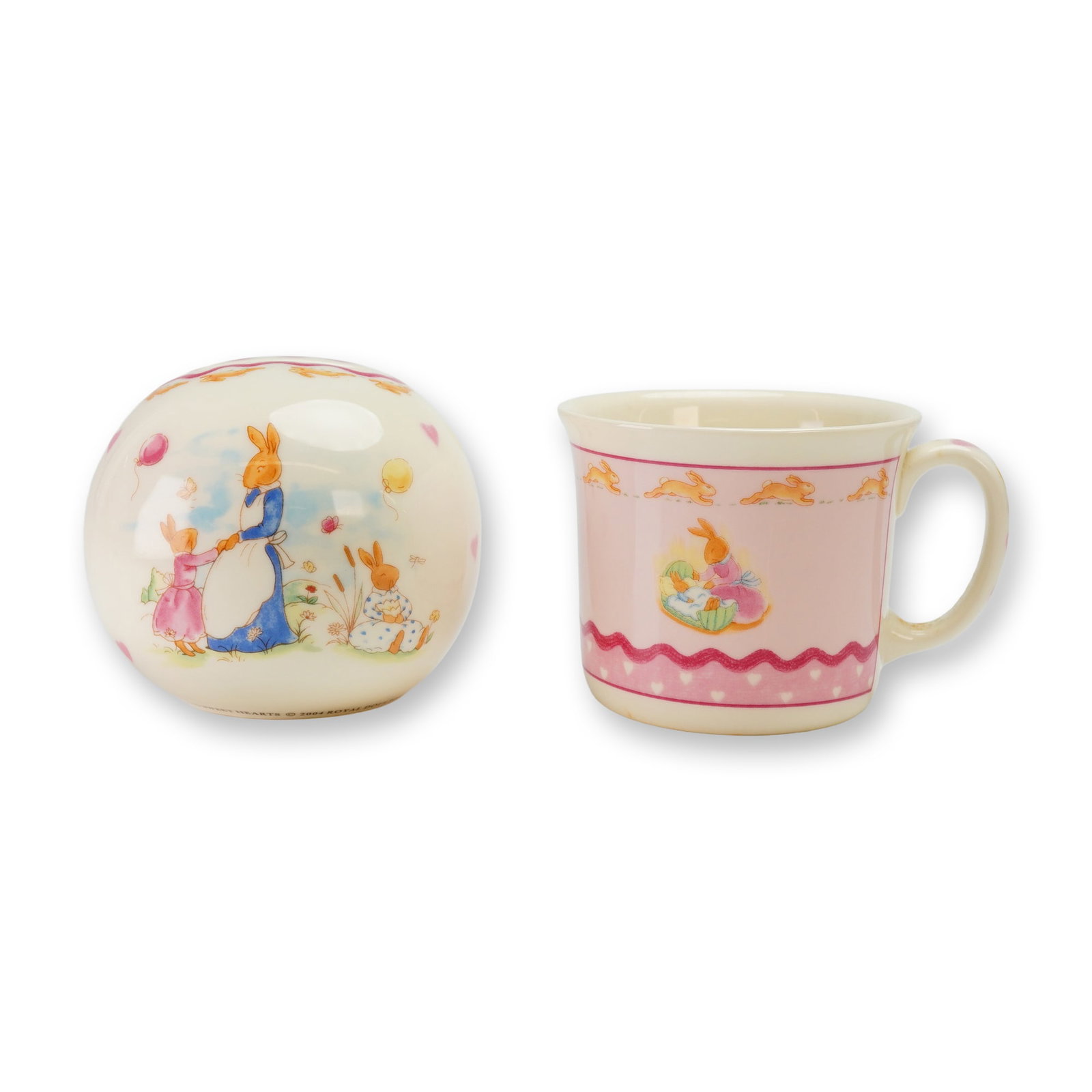 Two Royal Doulton Bunnykins Bone China Money Ball and Mug: A 2pc Royal Doulton Bunnykins bone china set in the Sweetheart H5317 pattern, consisting of a spherical money ball and a child's mug. Both pieces feature multi-color transfer-printed illustrations dep
