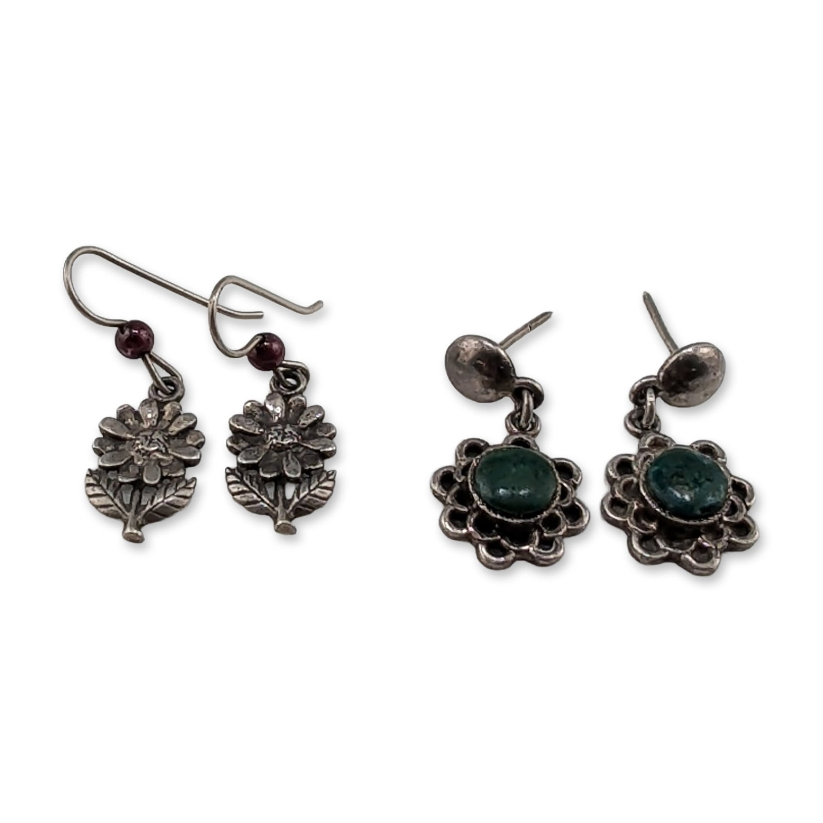 Two Pairs of Vintage Sterling Silver and 950 Silver Dangle Earrings: Group of two pairs of vintage silver drop earrings. The first pair features oval green cabochon stones set within scalloped floral borders and finished with post-style backings. The reverse of each ea