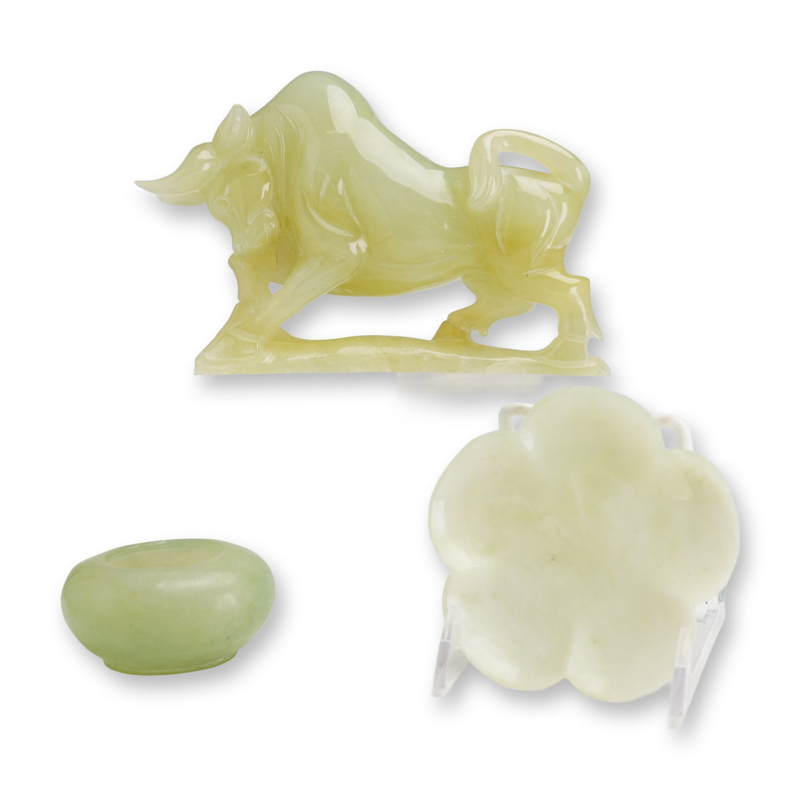 Three Chinese Style Carved Hardstone Figurine, Trinket Tray and Salt Cellar: Three Chinese style hand carved stone items, including a stylized charging bull, a foliate trinket tray, and a small oval bowl. Each piece is fashioned from varieties of pale green hardstone, likely s