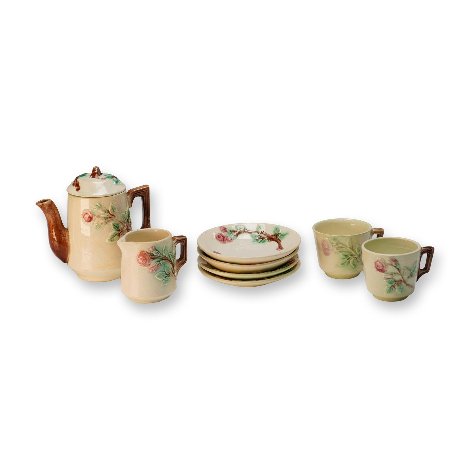 9pc Majolica Rose Design Pottery Child's Tea Set: A group of rose decorated pottery including four saucers, two teacups, one creamer, and one covered pitcher with its lid. Each piece is finished in a soft cream glaze with raised pink rose and green l
