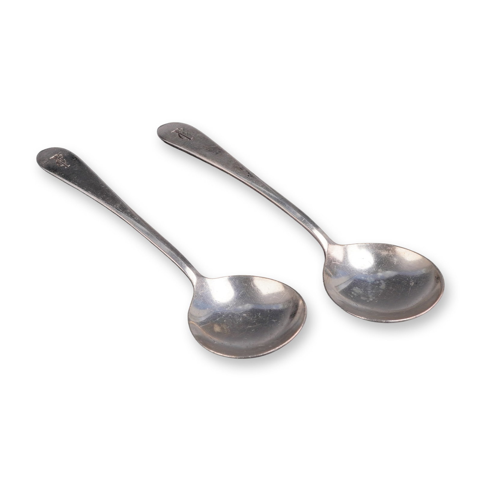 A Pair of International Silver Co. Silver-Plated Spoons: A pair of silverplated spoons produced by the International Silver Co. These items are designed as bouillon or cream soup spoons, featuring rounded bowls and smooth, tapered handles. Each spoon is