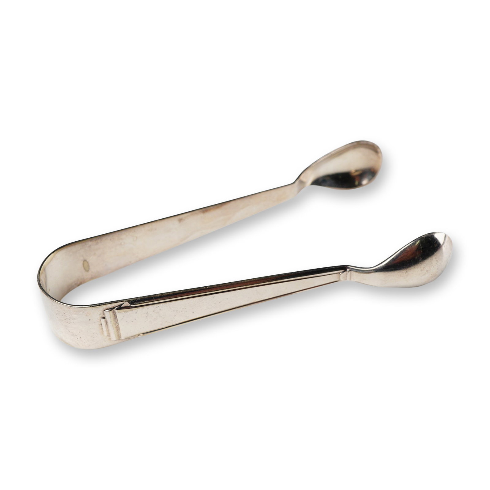 A Pair of Silver Plate Sugar Tongs, Marked R&B: A pair of silver-colored metal sugar tongs, featuring a simple, U-shaped design with unadorned, spoon-shaped grasping ends. The interior surface bears the initials 'R&B', a symbol, and the number