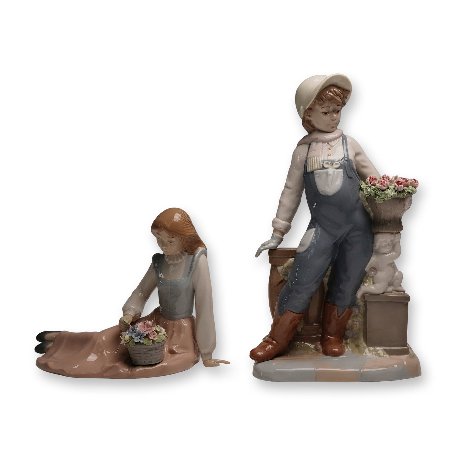 2pc Nadal Porcelain Figurine, Boy and Girl with Flower Baskets: A charming pair of hand-painted glazed porcelain figurines by Nadal, depicting a young boy and girl each with baskets of delicately modeled flowers. The boy stands in overalls and boots beside a