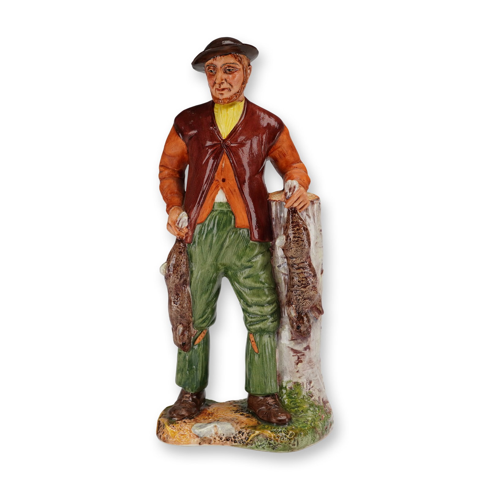 Coalport Bone China Figurine The Poacher: The figure depicts a man in rustic period clothing, including a brown hat, orange long-sleeved shirt, brown vest, and green trousers. He is portrayed holding two rabbits, with one in his right hand an