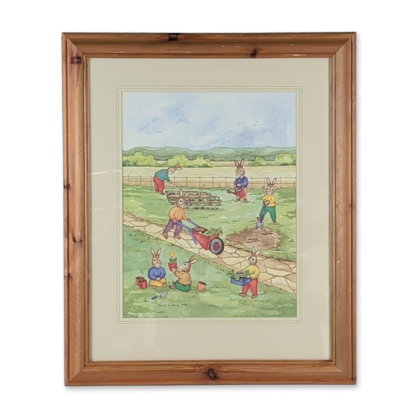 Denise Andrews 1994 Framed Original Watercolor Bunnykins Painting, Gardening: Housed in a wooden frame with a cream-color mat, a narrative garden illustration in watercolor and gouache on paper, featuring Bunnykins performing gardening tasks along a stone path. The composition 
