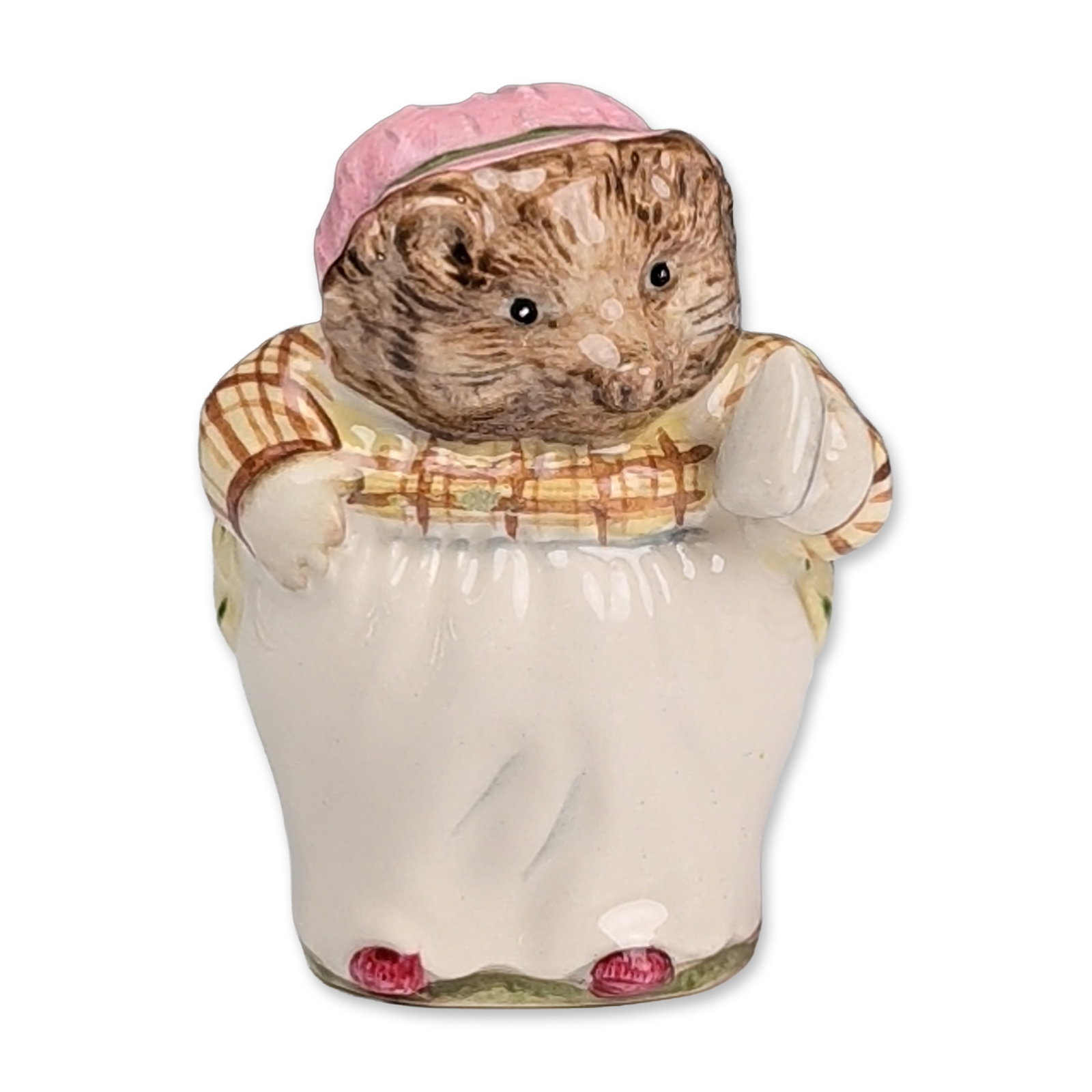 Royal Doulton Beatrix Potter Prototype Colorway Figurine, Mrs. Tiggy Winkle: The figure depicts the hedgehog character wearing a pink mop cap, a brown and yellow checkered shawl, a white apron, and a pink and green striped skirt while holding an iron. The base features a Royal