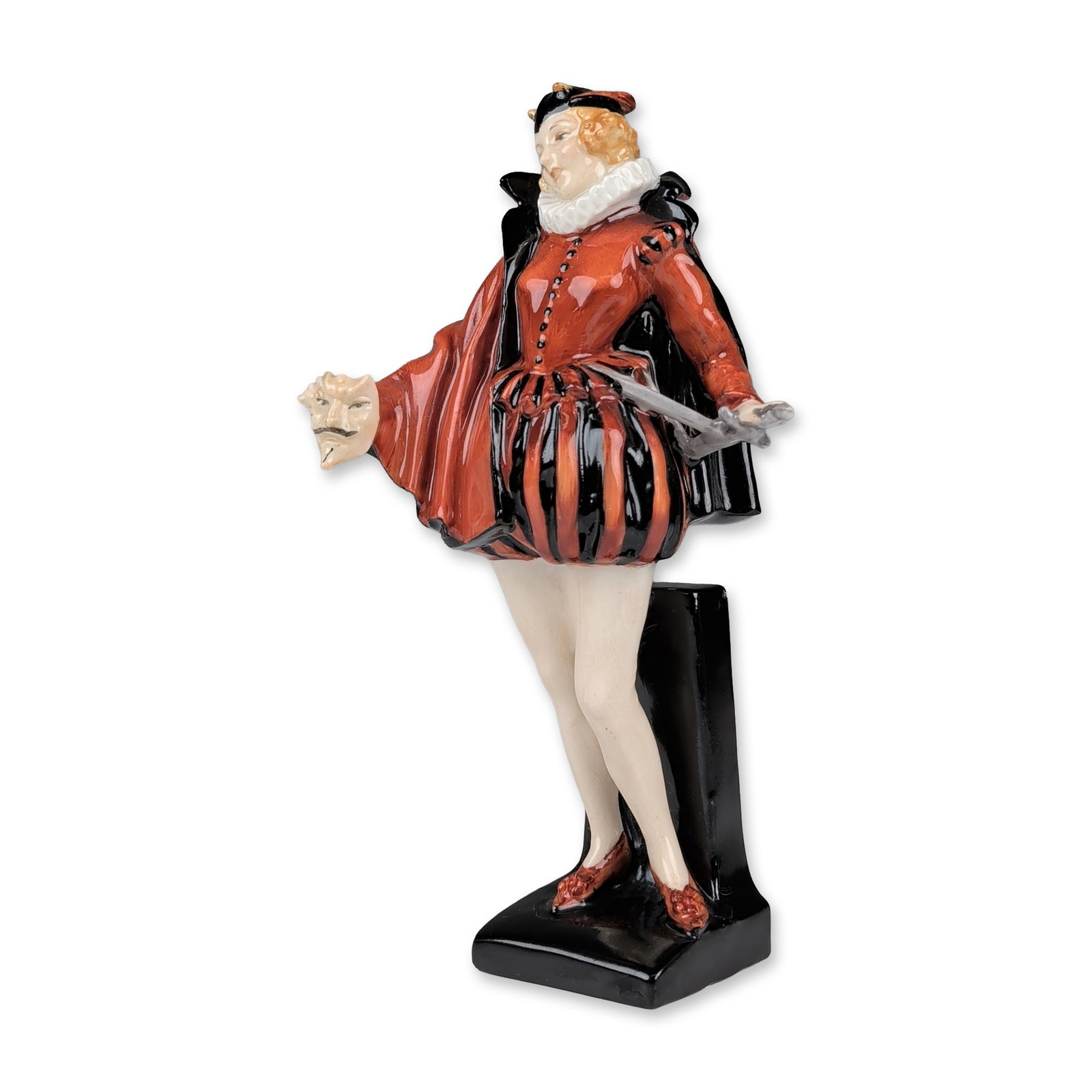Royal Doulton Porcelain Art Deco Figurine, Mephisto HN723: This character study from the Faust legend is depicted in a red doublet with a white ruff collar, black cape, and striped trunk hose. The figure stands on a black rectangular pedestal base holding a s