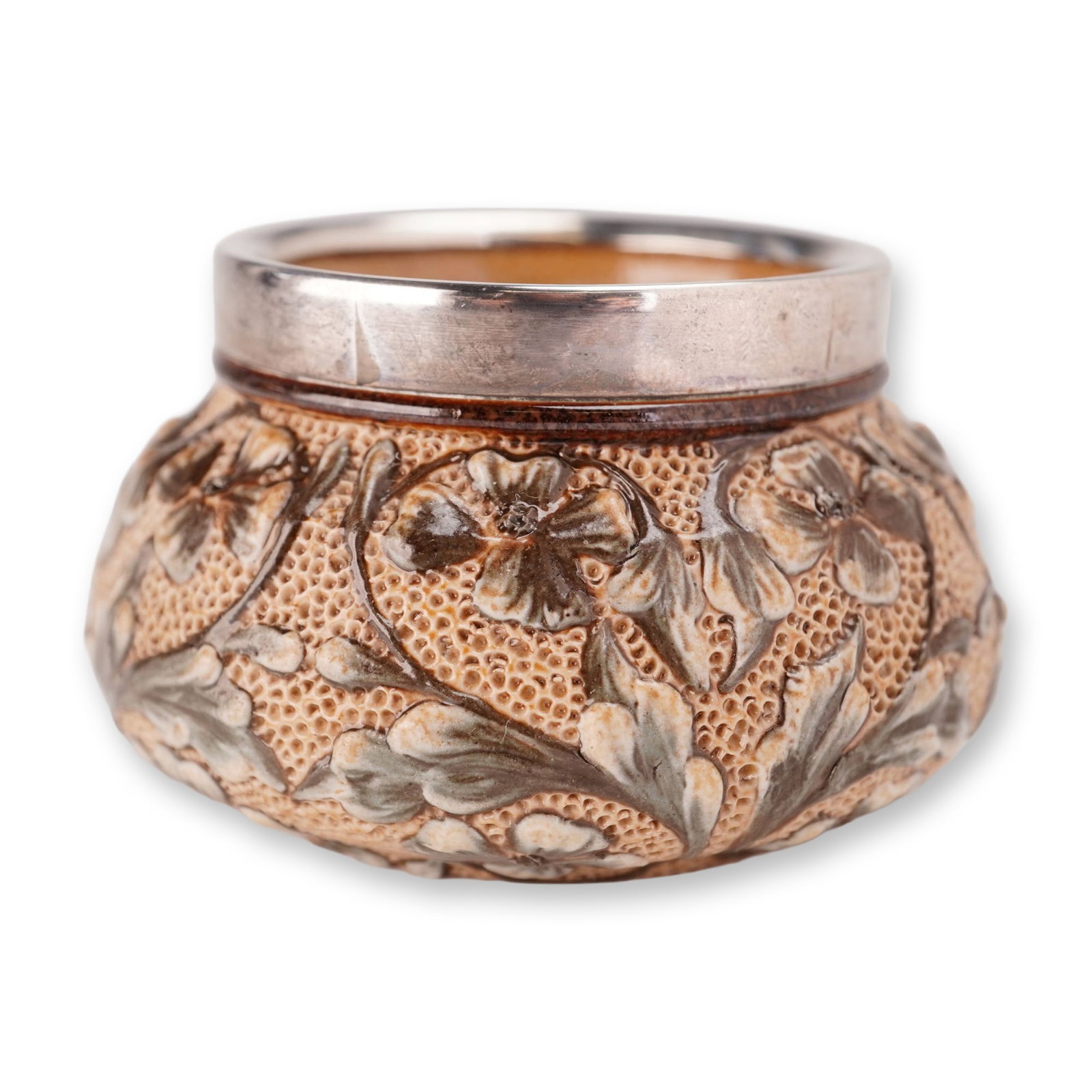 Doulton Lambeth Mary Barrett Stoneware and Silver-Plated Rim Floral Motif Open Salt: The bulbous body is decorated with hand-applied raised slip floral and foliate motifs in a palette of tan, brown, and grayish-green glazes. The vessel is fitted with a wide silver-plated metallic moun