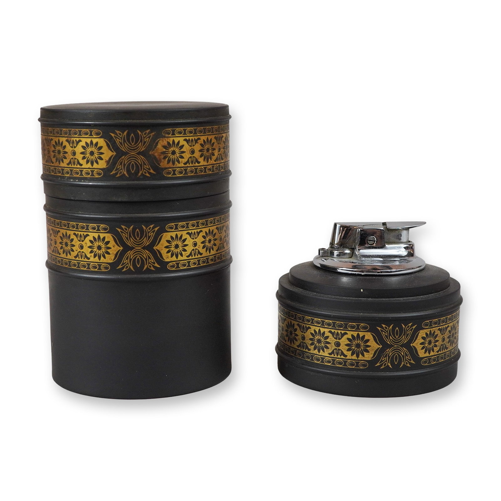 A Two-Piece Wedgwood Black Basalt and Gilt Stacking Smokers Set: A Wedgwood black basalt and gilt smoking set comprising a stacking cylindrical canister and a matching table lighter. Both components are constructed from matte black basalt ceramic decorated with hor