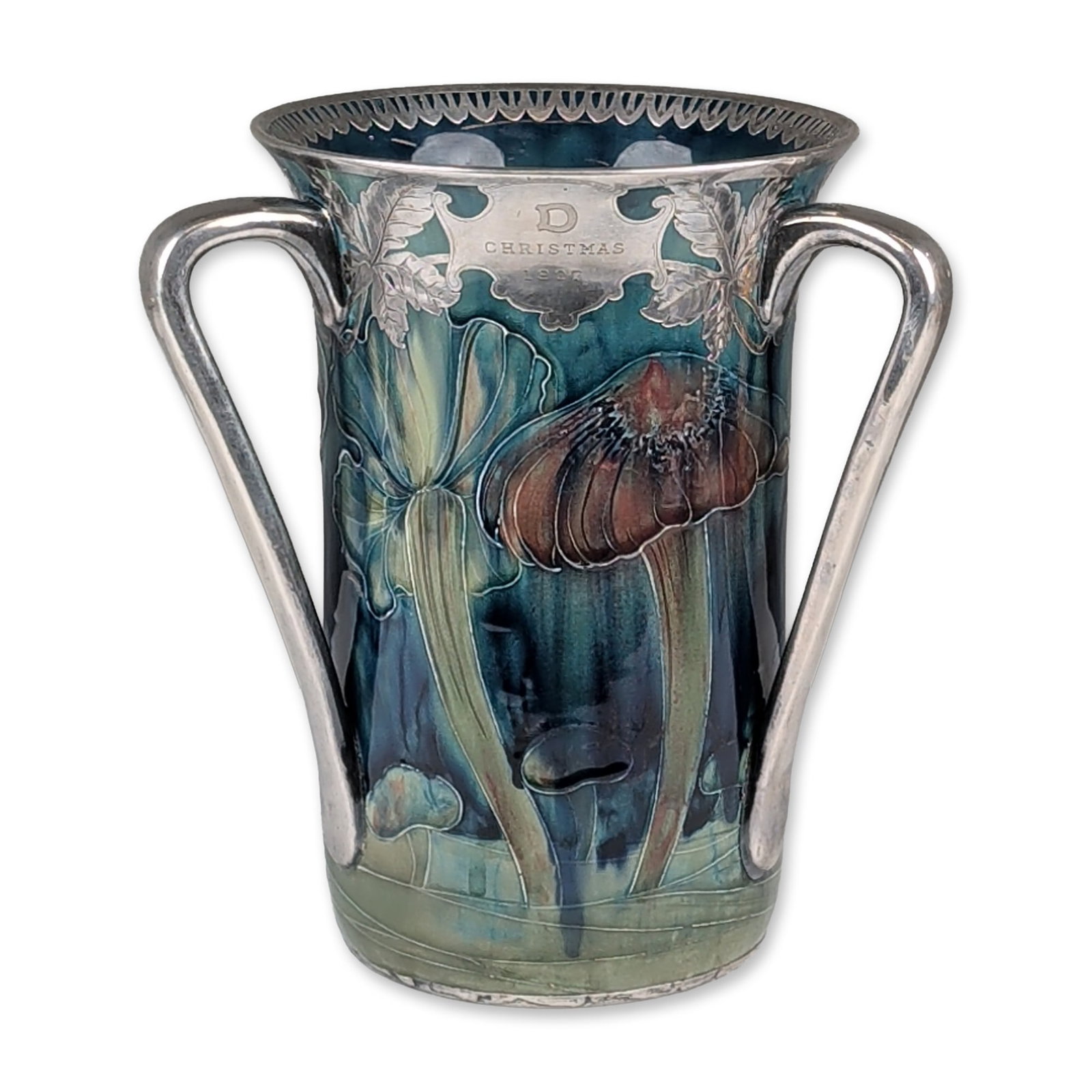 William Moorcroft Macintyre Pottery and Shreve & Co. Sterling Mounted 1907 Christmas Tyg, Claremont: The ceramic body is richly decorated with tube-lined mushrooms in a vibrant palette of deep blue, teal, sage green, red, and ochre. The vessel is mounted in finely crafted silver by Shreve & Co. of Sa