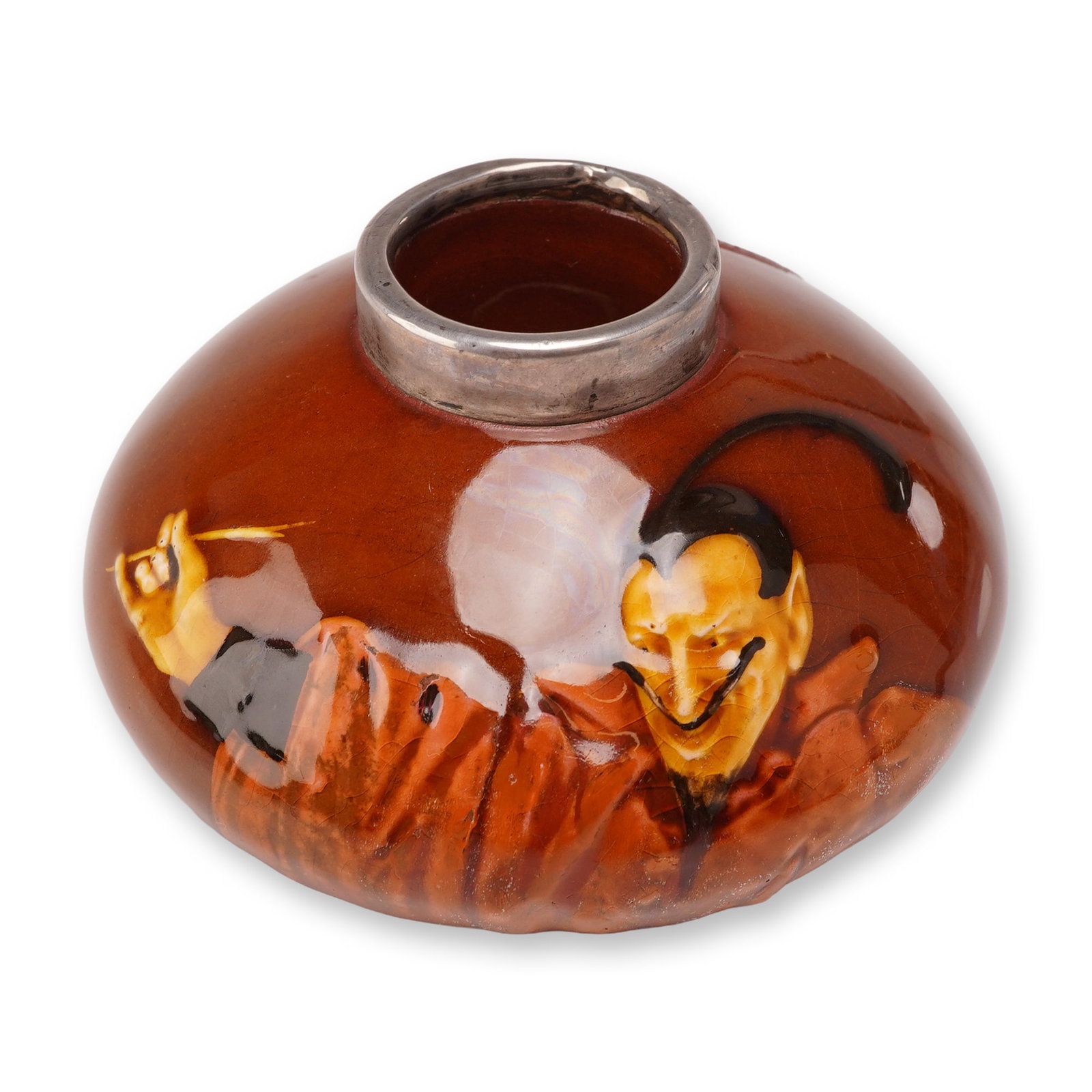 Royal Doulton Very Rare Mephistopheles Kingsware Match Striker with Sterling Silver Rim: The vessel features a dark brown treacle glaze and is decorated with a low relief figure of Mephistopheles rendered in shades of orange and yellow. The reverse side displays a textured, heart-shaped m