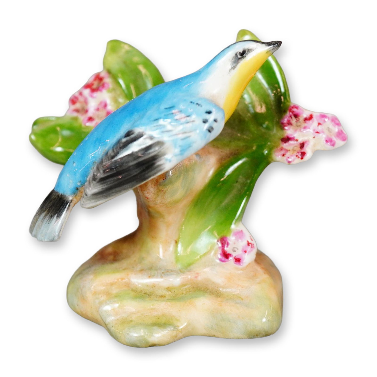 Royal Doulton Bone China Bird Figurine, Yellow-Throated Warbler K27: Hand-painted Royal Doulton figure of a vibrant warbler featuring a yellow throat, blue body plumage, and black detailing on the wings and tail feathers. The bird is perched alongside pink blossoms. Ro