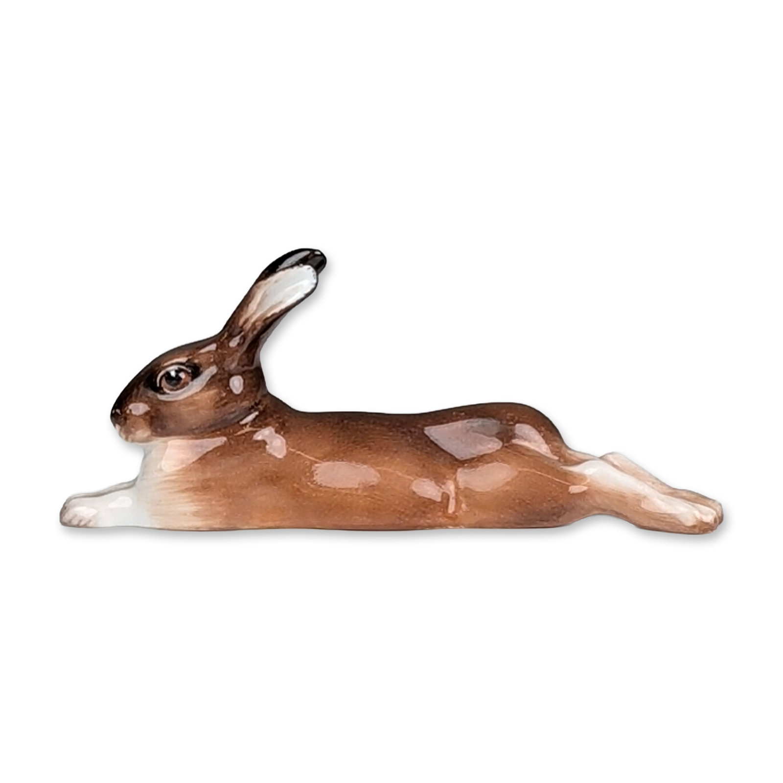 Royal Doulton Porcelain Figurine, Hare Lying Legs Stretched HN2594: Figurine in glazed porcelain, depicting a hare in a lying position with legs stretched and ears laid back. The piece features a variegated brown and tan glaze with dark accents to the ear tips and eye