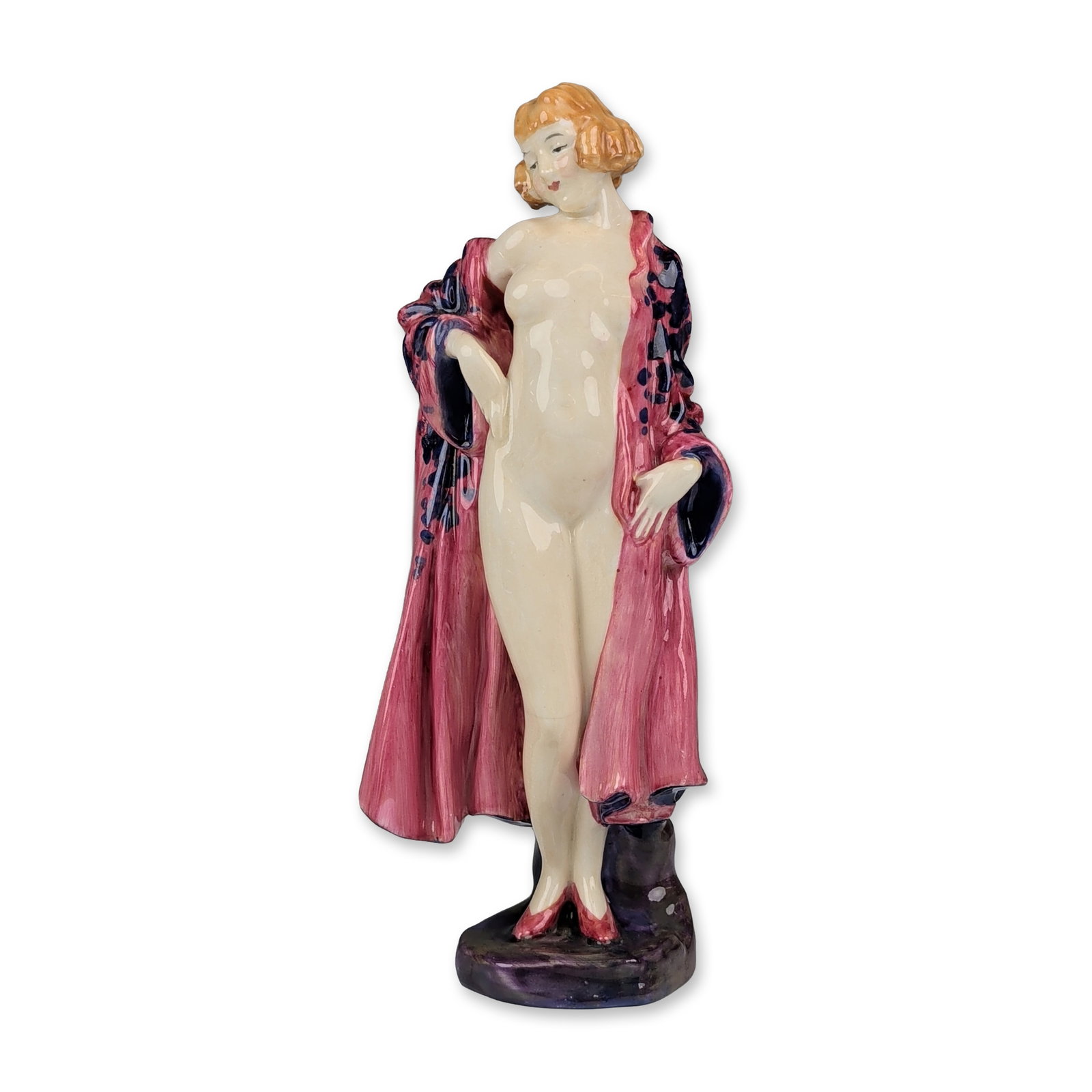 Royal Doulton Art Deco Porcelain Figurine, The Bather HN773: The piece depicts a nude female figure with reddish-blonde bobbed hair partially draped in a rose-pink robe decorated with dark blue stylized spots. The figure stands on an irregular mottled dark purp