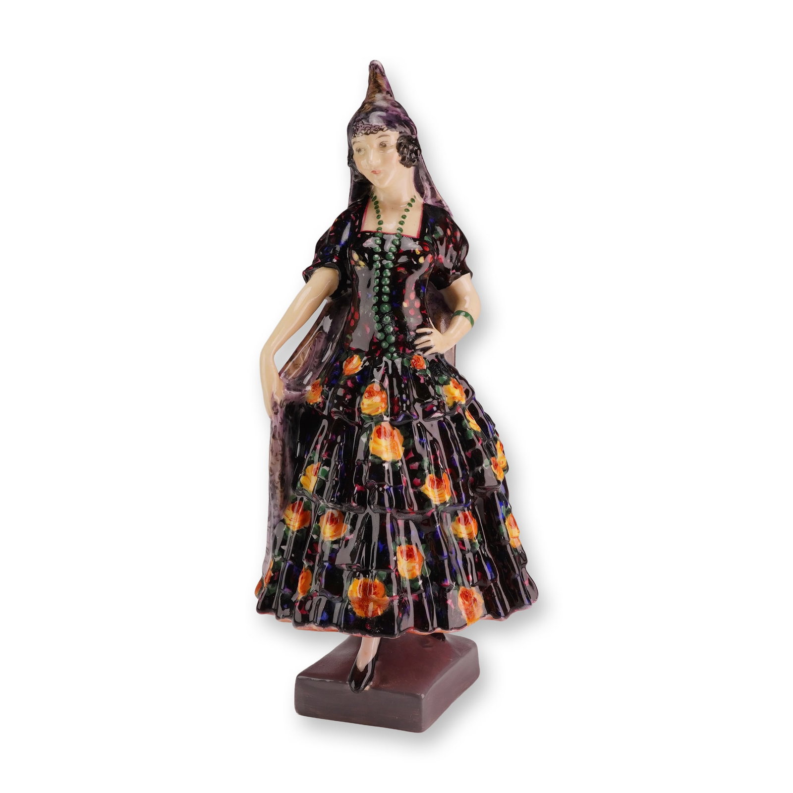 Royal Doulton by Leslie Harradine Figurine, Spanish Lady HN1293, Very Rare Version.: The figure depicts a woman in traditional Spanish attire. She is dressed in a voluminous black gown featuring three-tiered ruffles decorated with a hand-painted pattern of orange and yellow roses. A t