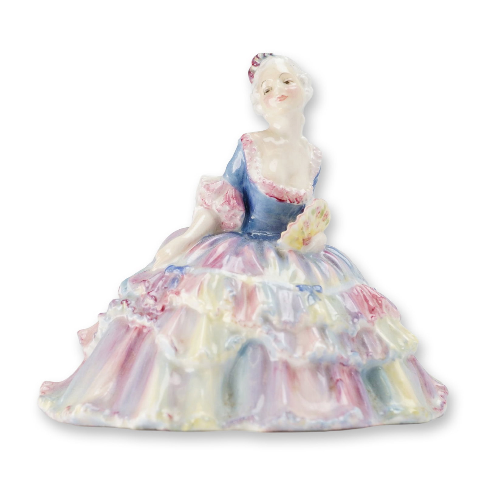 Royal Doulton Porcelain Figurine, Lisette HN1524: Designed by Leslie Harradine. The figure depicts a seated woman in 18th-century style dress, featuring an elaborate tiered ruffled gown in pastel shades of pink, yellow, and light blue, holding a hand