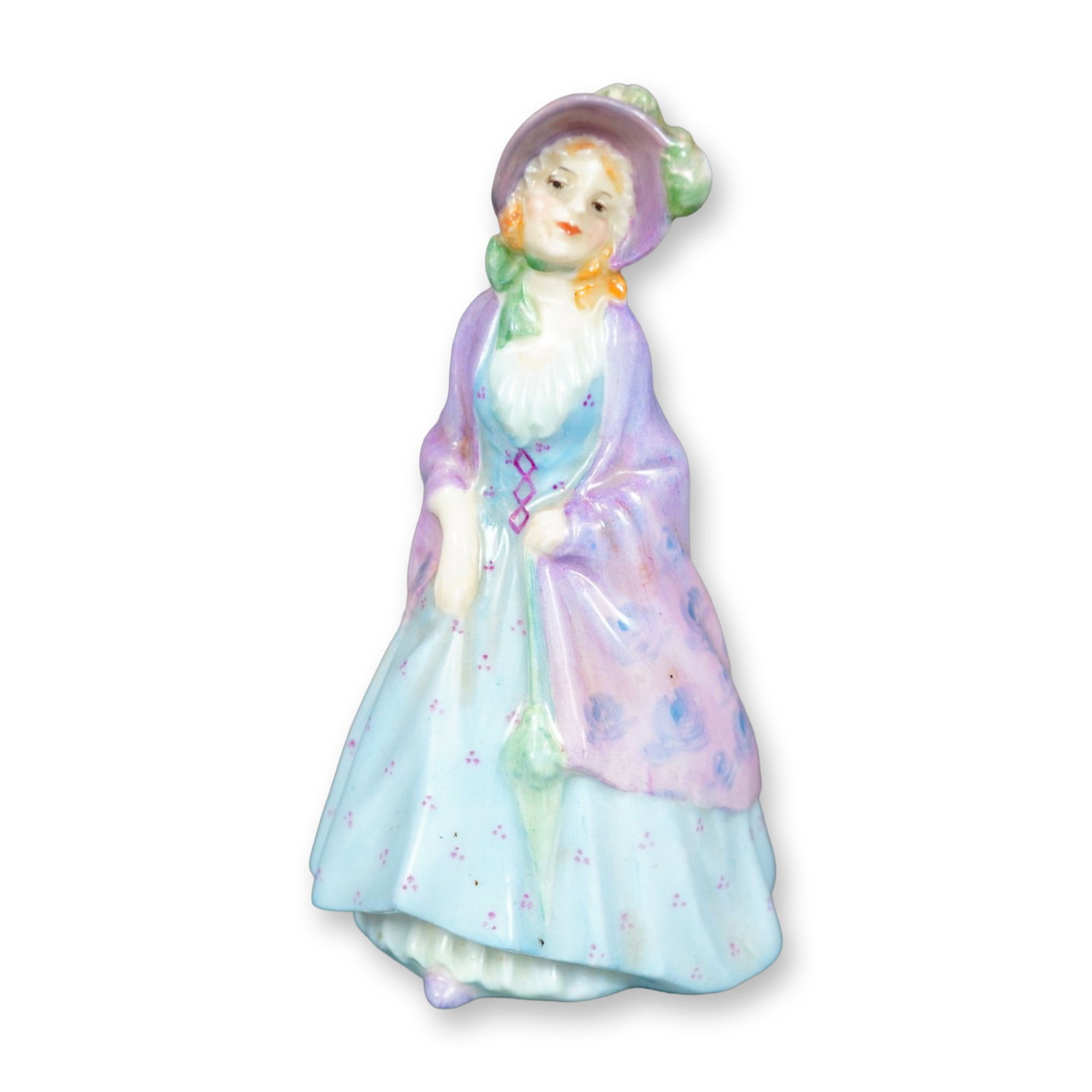 Royal Doulton Figurine, The Paisley Shawl M3: Hand painted figure of a woman in a blue dress, pink-purple shawl, and a pink hat with green accents. The gown and shawl are decorated with a floral pattern. Royal Doulton backstamp. Dimensions: 2.25"