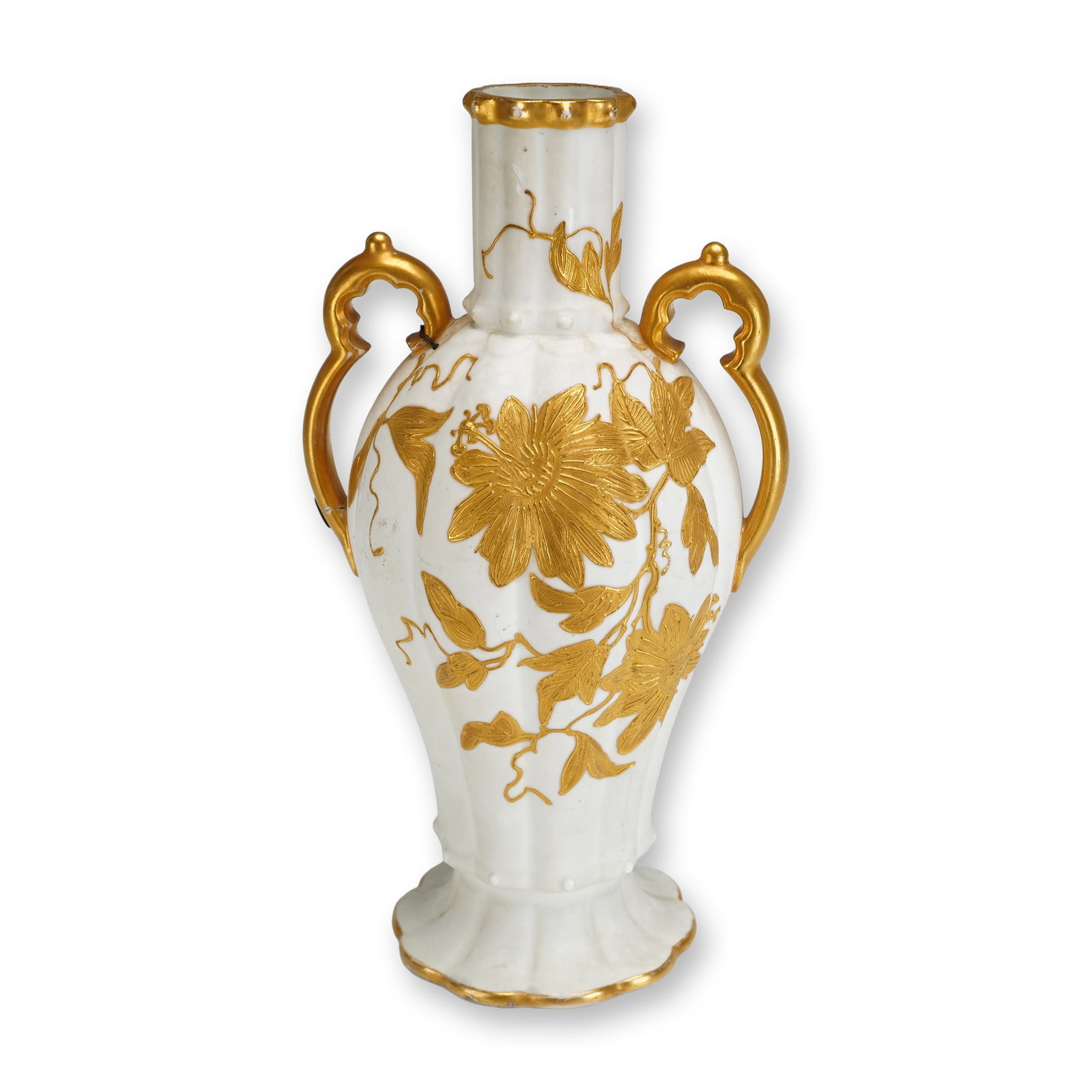 Wedgwood Gilded Ivory Ware Double-Handled Vase, c. 1880: This double-handled porcelain vase is crafted in Wedgwood Ivory Ware, characterized by its lobed, fluted body and creamy matte finish. The vessel tapers to a scalloped pedestal foot and is decorated w