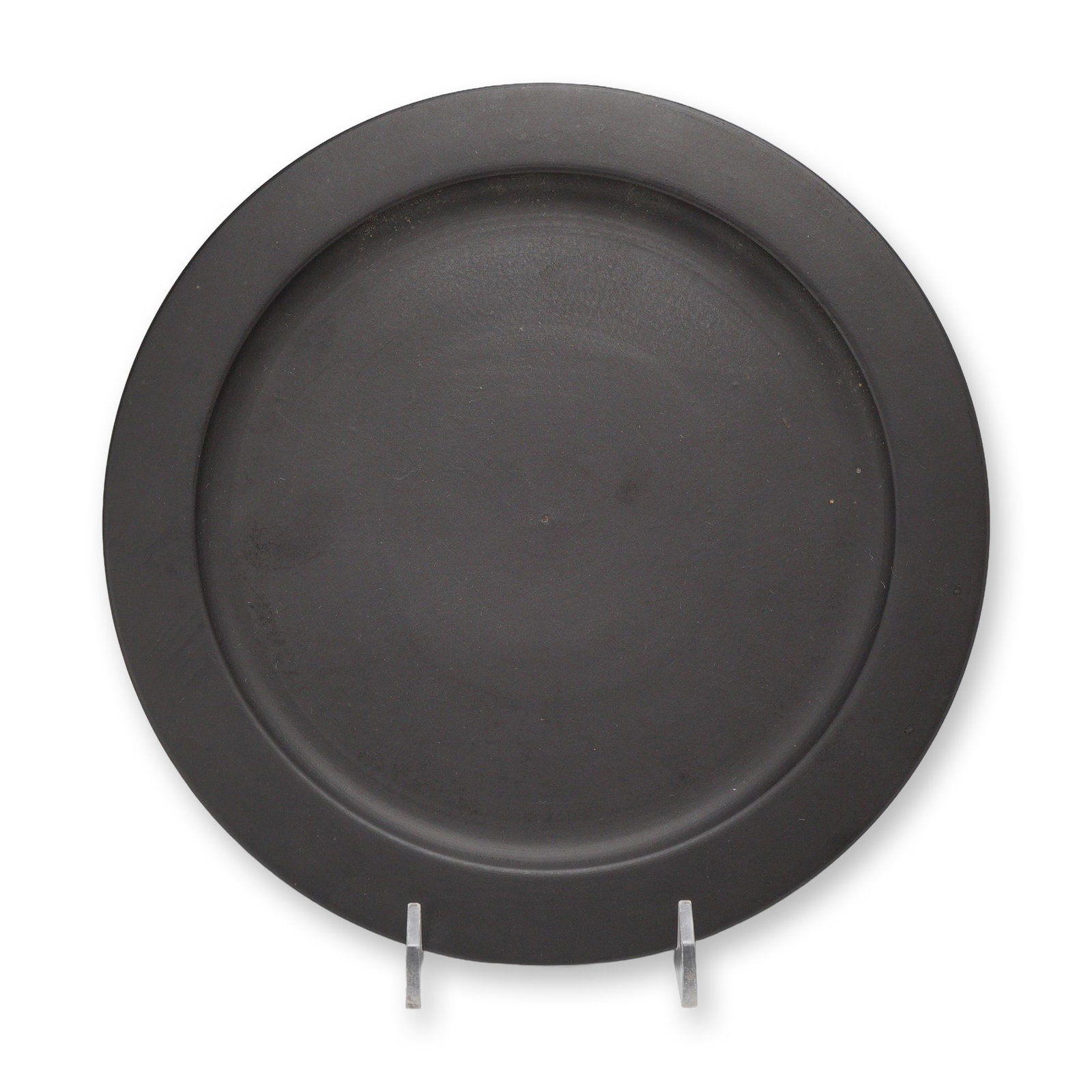 Wedgwood Black Basalt Charger Platter: A Wedgwood black basalt stoneware charger platter featuring a circular form with a wide, flat rim and a shallow, recessed center. The piece is characterized by the smooth, unornamented matte black fin