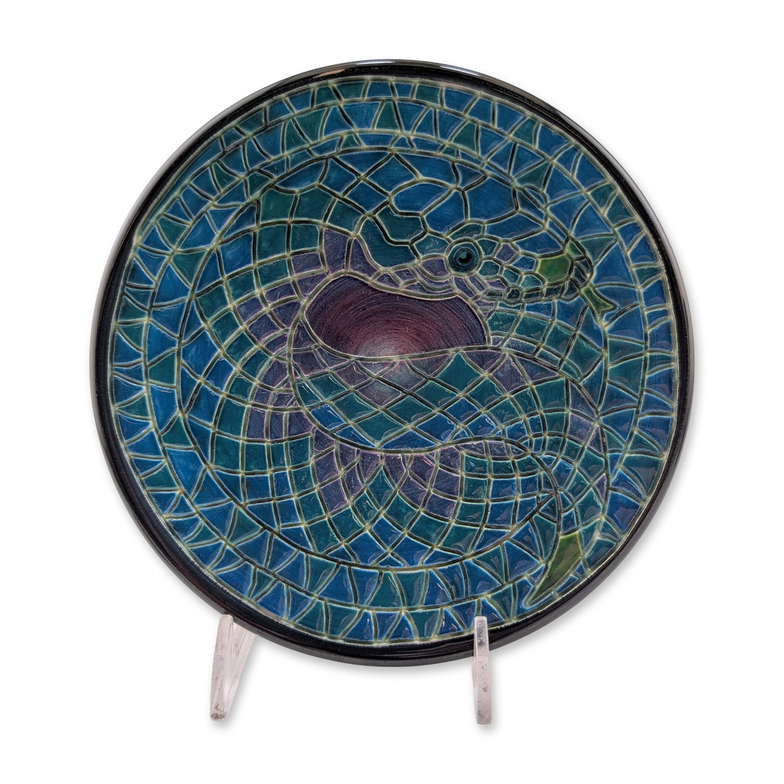 Dennis China Works Sally Tuffin Snake Ceramic Plate: This contemporary earthenware piece features an incised slip design of a coiled serpent in a mosaic pattern, utilizing translucent cobalt blue, teal, and sage green glazes against a dark purple center