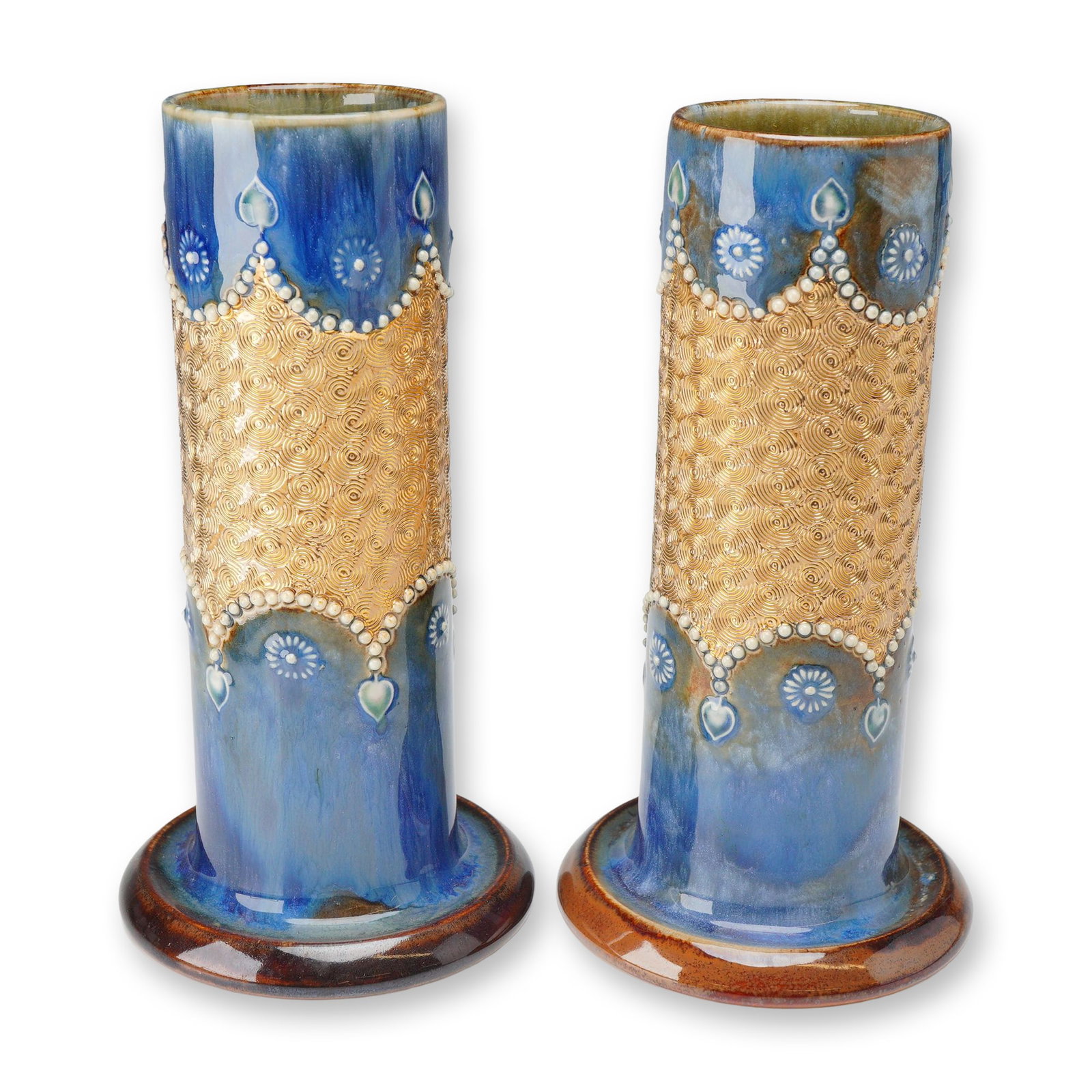 Pair of Royal Doulton Gilt Circle Ware Vases: A set of two cylindrical vases with wide bases, finished in blue and brown tones. Each vase features a central Gilt Circle pattern accented with white beaded floral and foliate relief decoration. Roya