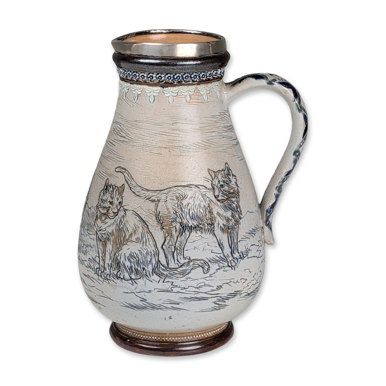 Doulton Lambeth by Hannah Barlow Stoneware and Sterling Silver Rim Cat Motif Pitcher: Jug in salt-glazed stoneware, featuring sgraffito decoration by Hannah Barlow depicting four cats in a field. The neck displays cobalt blue raised floral medallions and white slip-trailed lace details