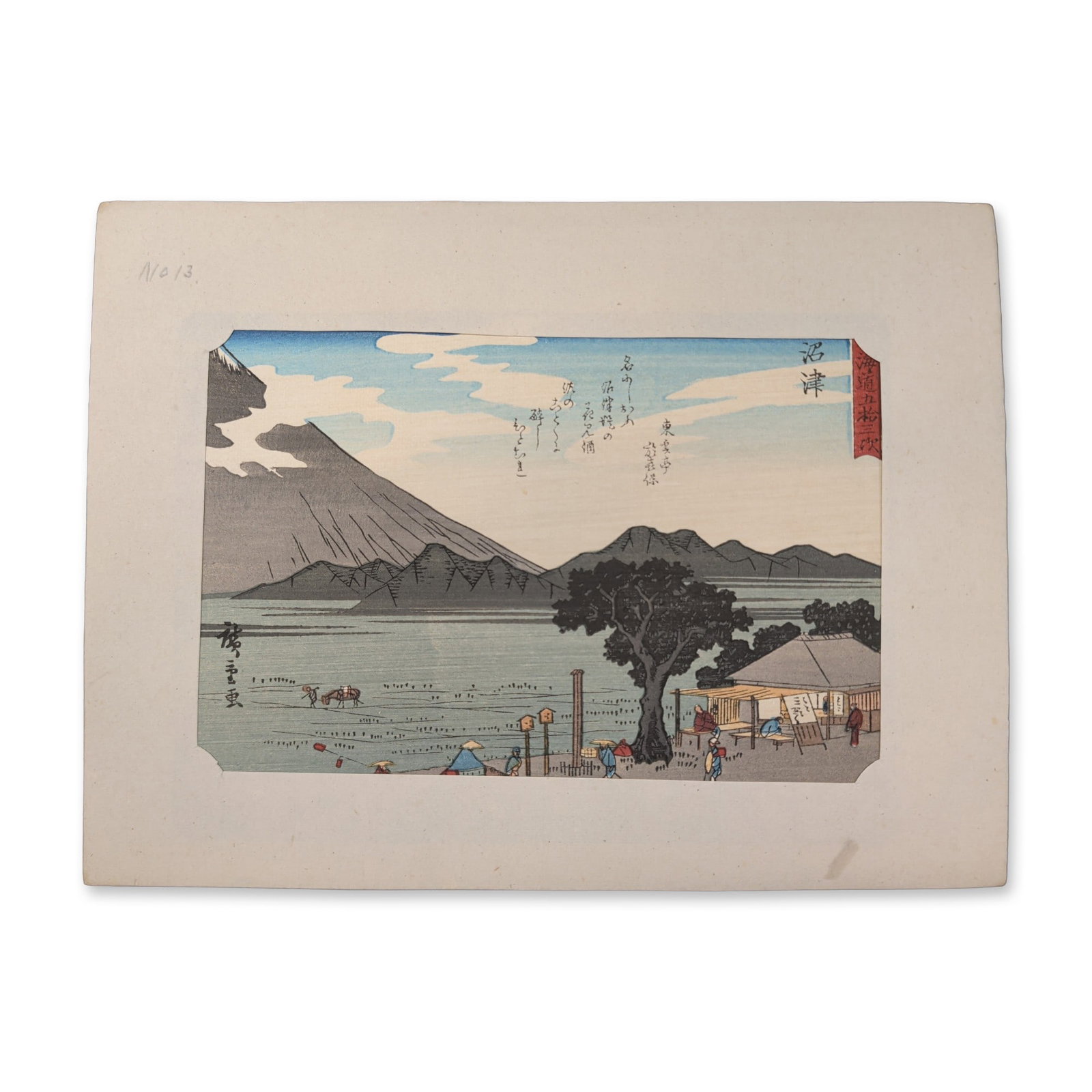 After Utagawa Hiroshige (Japanese 1797-1858) Numazu: From a Fifty-three Stations of the Tokaido: A scattering of travelers navigates a flat shoreline path stretching past a small cluster of thatched open-air teahouses shaded by a prominent pine tree. The massive, snow-capped cone of Mount Fuji do