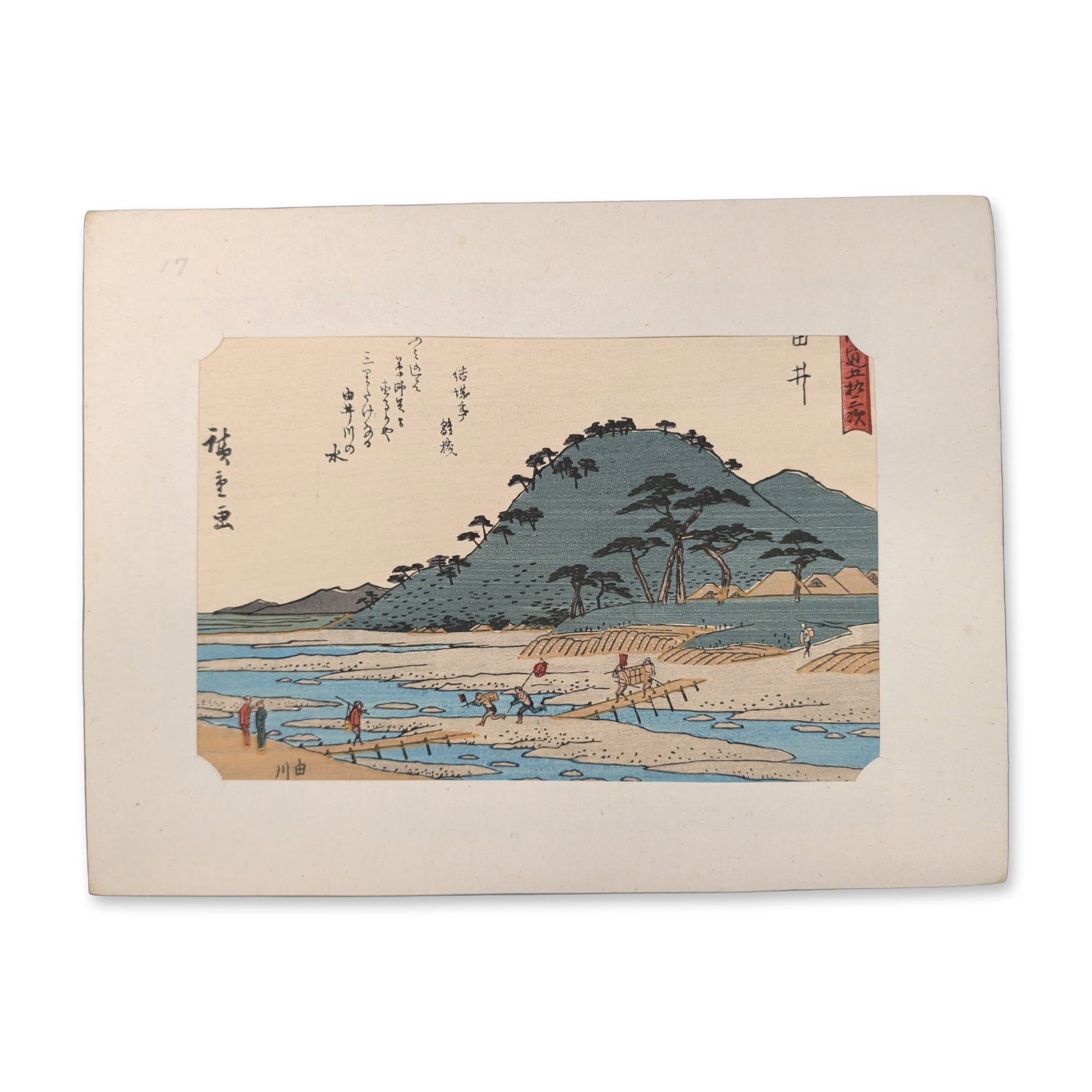 After Utagawa Hiroshige (Japanese 1797-1858) Yui, Fifty-Three Stations of the Tokaido Woodblock: A horizontal format landscape composition centers on traveler figures crossing a small wooden footbridge over an estuary by Utagawa Hiroshige. A large, foliage-covered hill mound dominates the right f