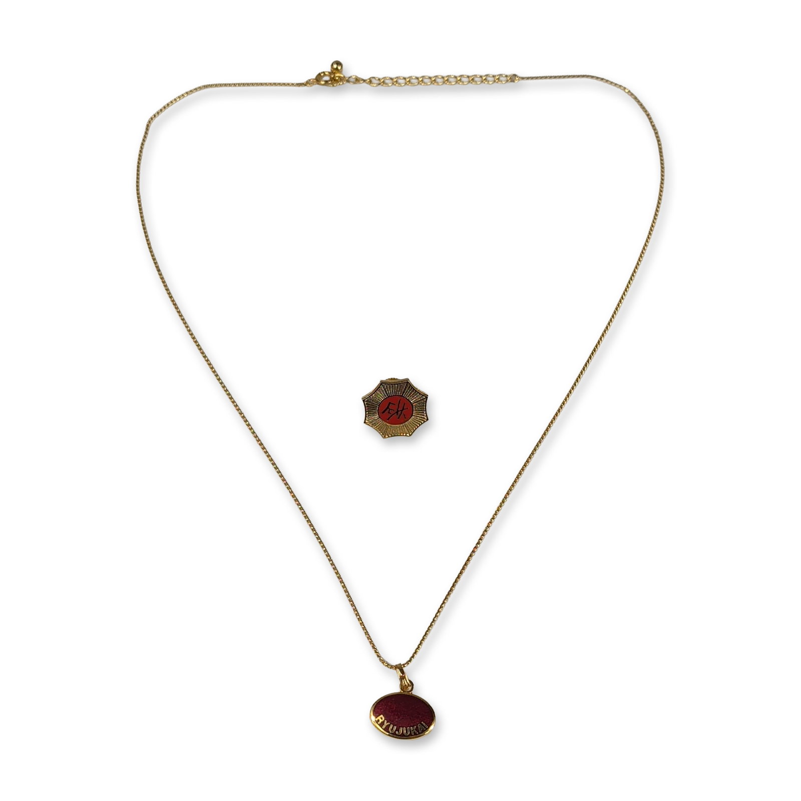 2pc Ryujukai Gold-Tone Necklace and Lapel Pin: Ryujukai association jewelry set in gold-tone metal with red-colored centers. The group includes a thin link chain necklace and a matching octagonal lapel pin. The necklace features an oval pendant wi