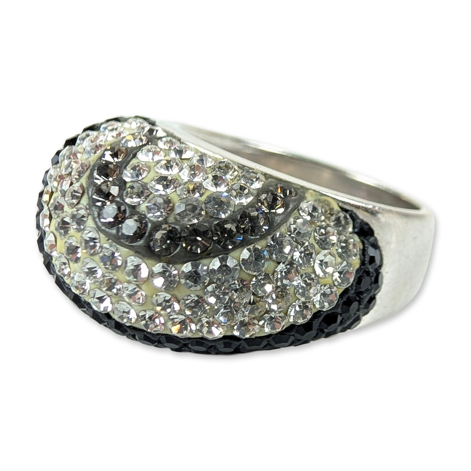 JCM Sterling Silver Pave Swirl Cocktail Ring: JCM (Thailand). Cocktail ring in sterling silver featuring a bold domed head with a stylized wave pattern. The design is set with contrasting bands of clear and black round faceted stones in a pave se