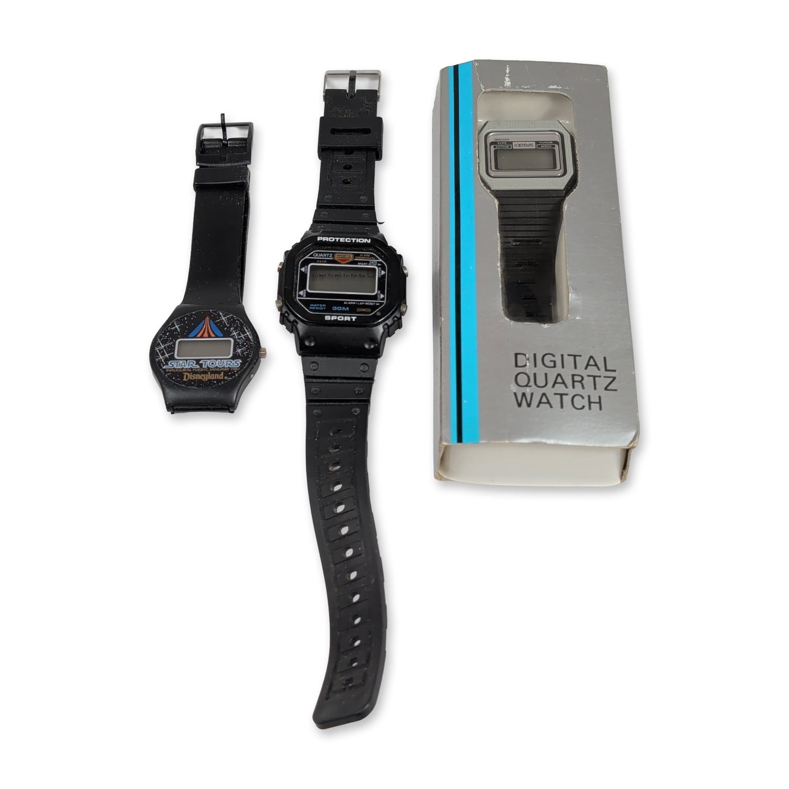 3pc Vintage Digital Wristwatches: Trio of vintage digital wristwatches. The lot includes a Braddex digital quartz watch in its original silver-tone cardstock box, featuring a silver-tone resin case and black ribbed strap. All three wa