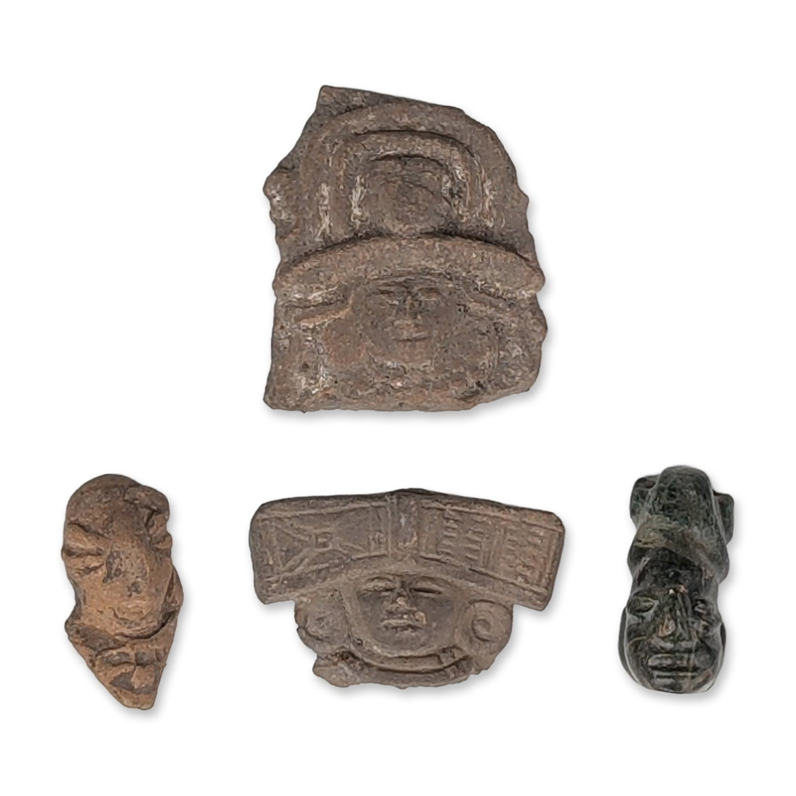 4pc Pre-Columbian Figural Head Fragments in Clay and Stone: The collection includes three terracotta examples and one carved dark greenstone head. The largest terracotta fragment depicts a face with a triple-tiered arched headdress and mold-made features. A