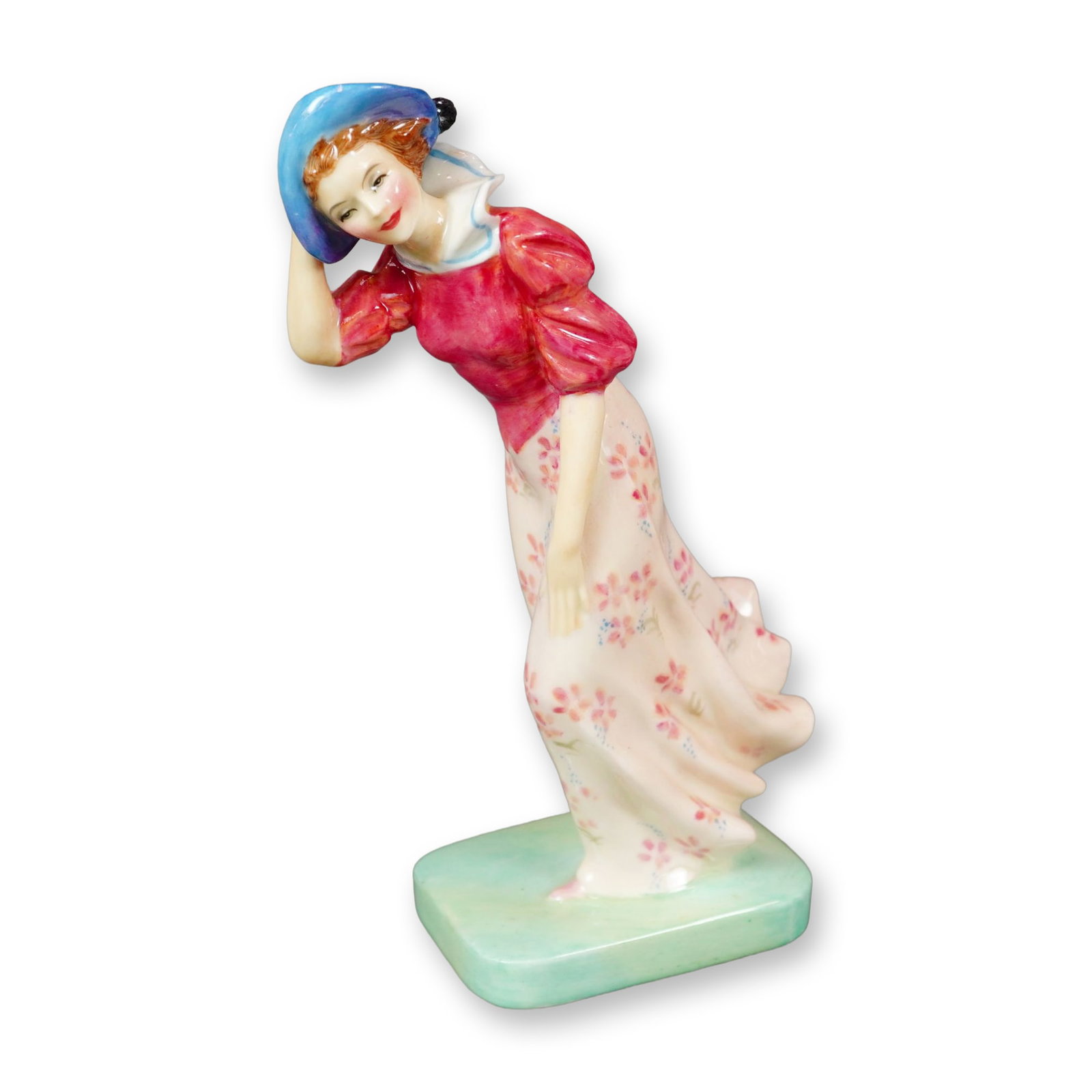 Royal Doulton Bone China Figurine, Windflower HN1763: Part of the Harradine Classics series, this hand-painted Royal Doulton figure was designed by Leslie Harradine. The piece depicts a woman wearing a pink floral skirt and matching pink blouse, posed as