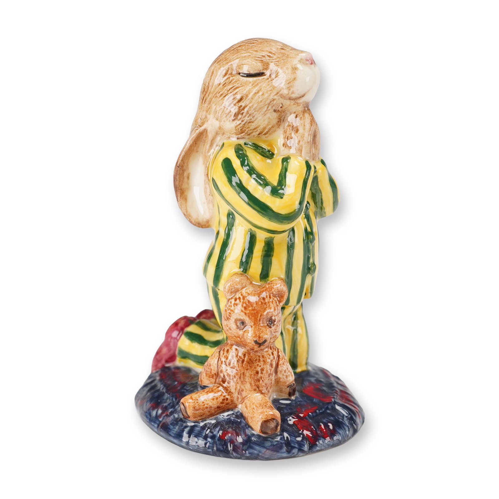 Royal Doulton Bunnykins Colorway Artist Copy Figurine, Bedtime: The porcelain figure depicts a rabbit kneeling in striped yellow and green pajamas with red slippers, hands clasped in front, and a small teddy bear seated on the textured base. The underside bears th