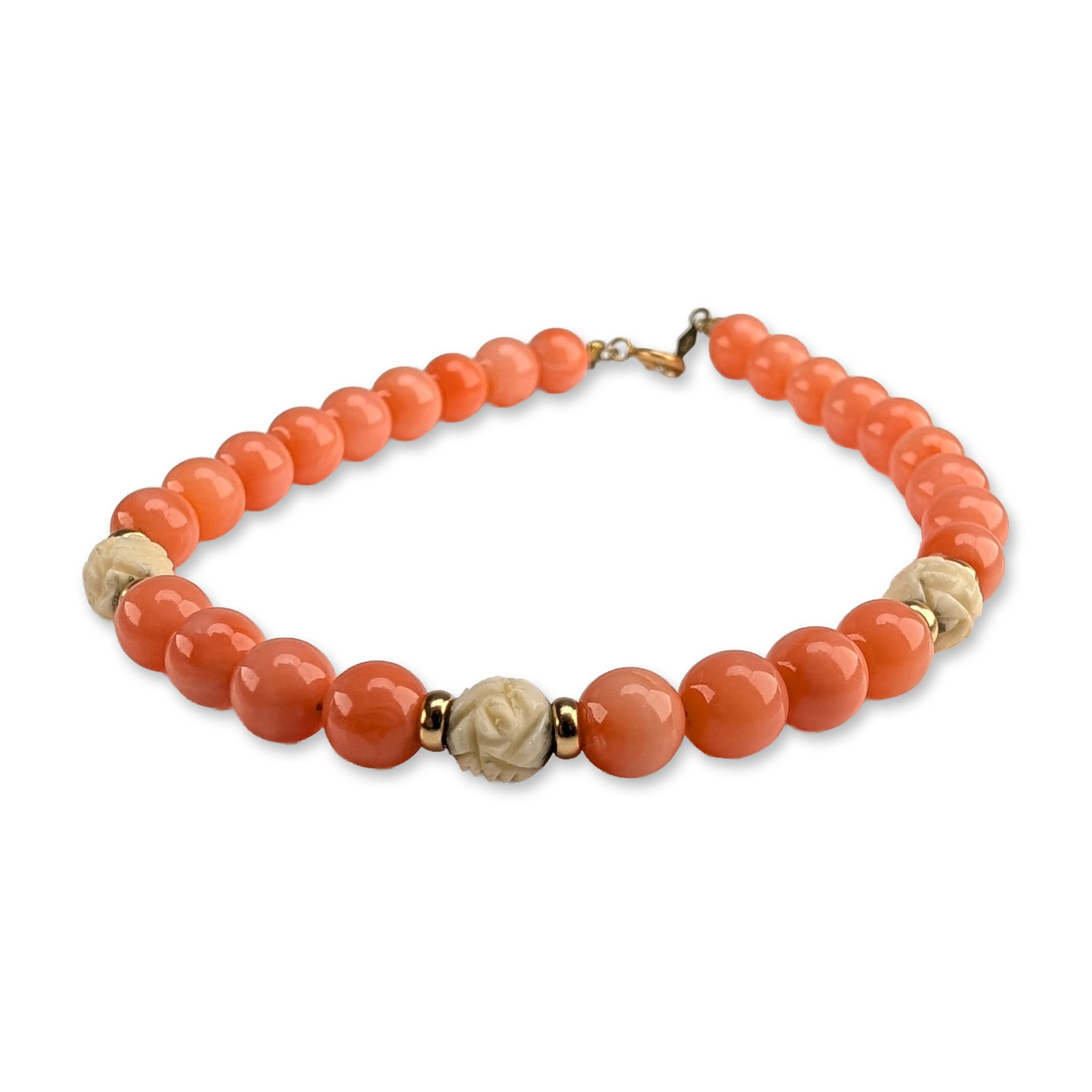 14K Gold Salmon Coral and Carved Bead Bracelet: Beaded bracelet featuring polished salmon-colored coral beads and three white carved rose-motif beads. The piece is accented with six gold spacer beads flanking the carved elements and is secured with