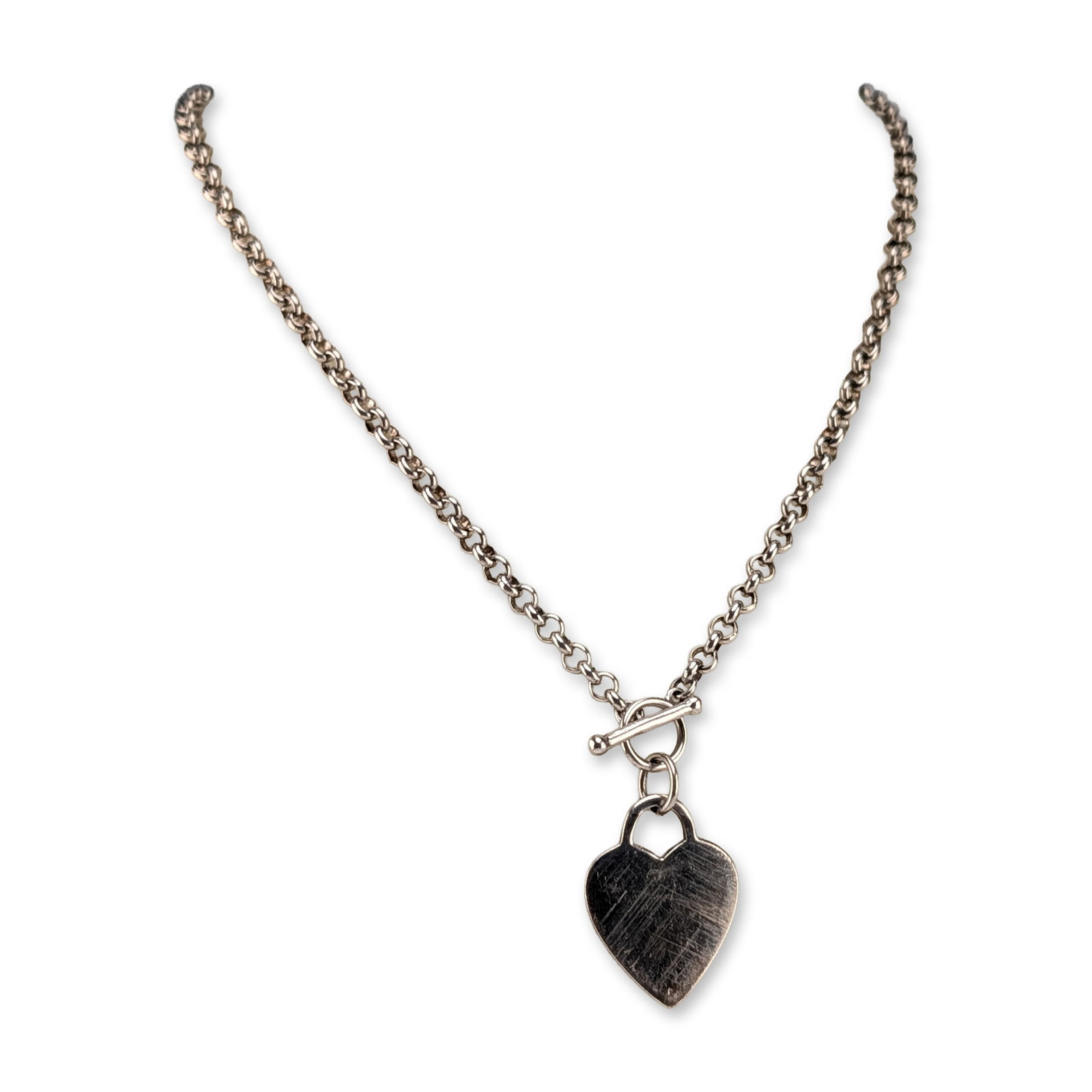 Sterling Silver Heart Tag Toggle Necklace: Sterling heart tag toggle necklace featuring a heavy gauge rolo link chain. The necklace is secured with a front-facing toggle clasp assembly from which a solid heart-shaped tag pendant is suspended b