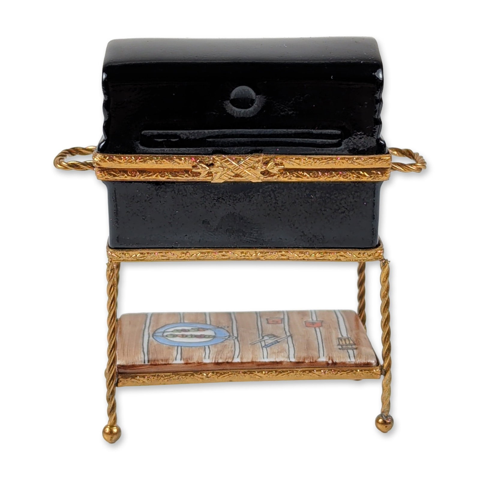 Limoges HF French Porcelain Barbecue Grill Trinket Box: A French Limoges porcelain trinket box by HF designed as a barbecue grill on a stand. The black-glazed porcelain box is mounted in a gold-toned metal frame with a hinged lid and bow-shaped clasp. The 