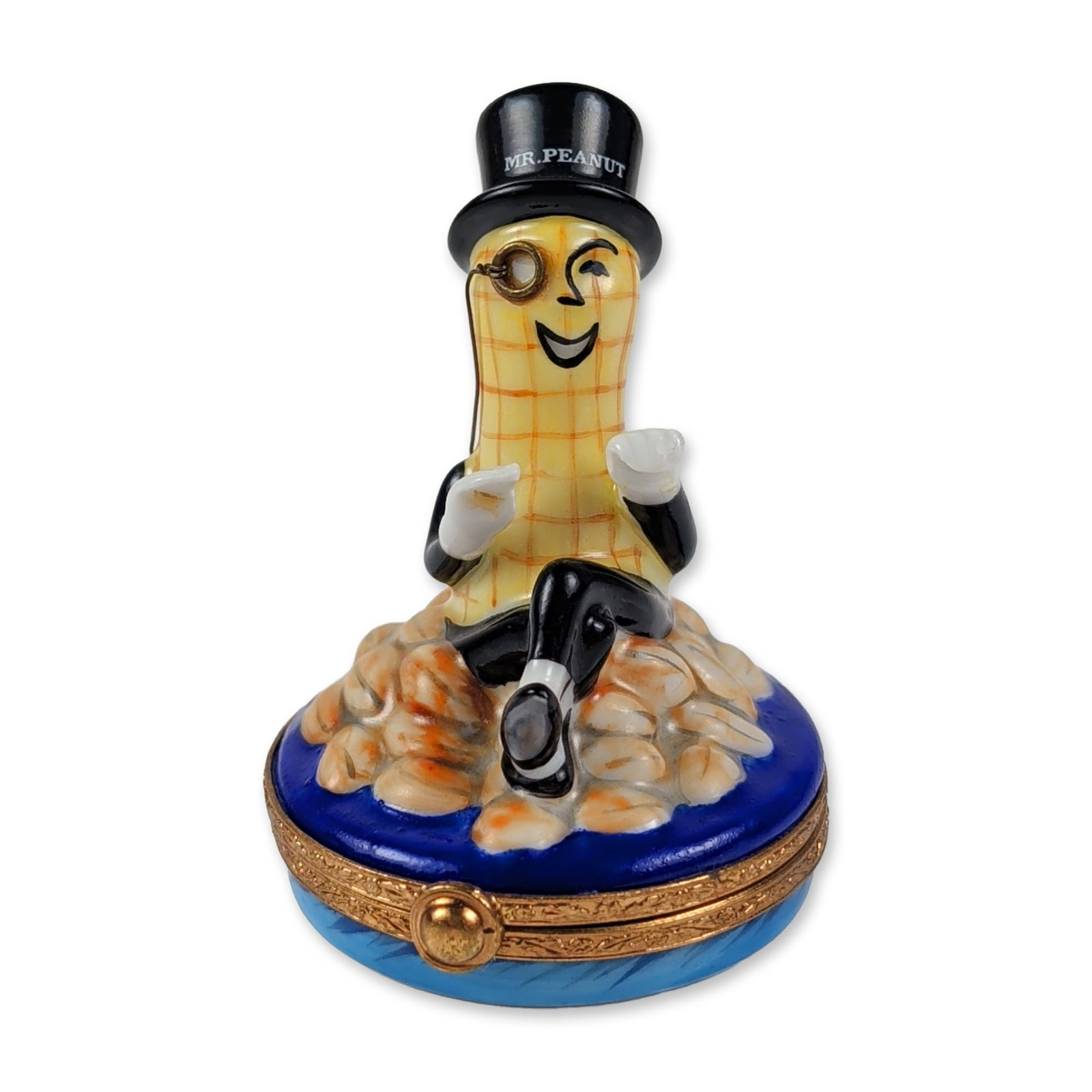 Limoges Mr. Peanut Porcelain Trinket Box: Artoria Limoges hand-painted porcelain trinket box featuring the Planters mascot Mr. Peanut. The figure is depicted wearing a black top hat, monocle, and white gloves, seated upon a mound of shelled p