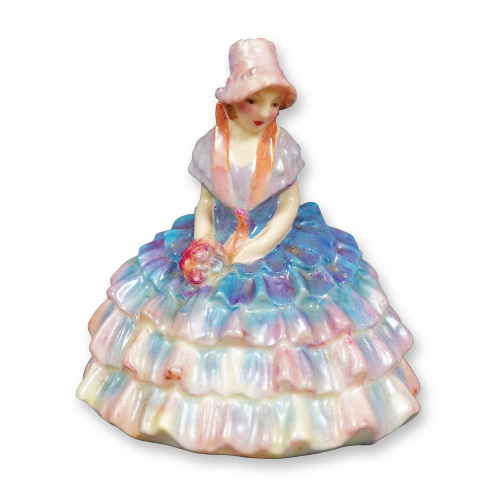 Royal Doulton Figurine, Chloe M010: Hand painted figure of a seated woman in a blue and pink ruffled gown. She is holding flowers on her lap. Royal Doulton backstamp. Dimensions: 2.75"L x 2"W x 2.75"H Manufacturer or Brand: Royal Doulto